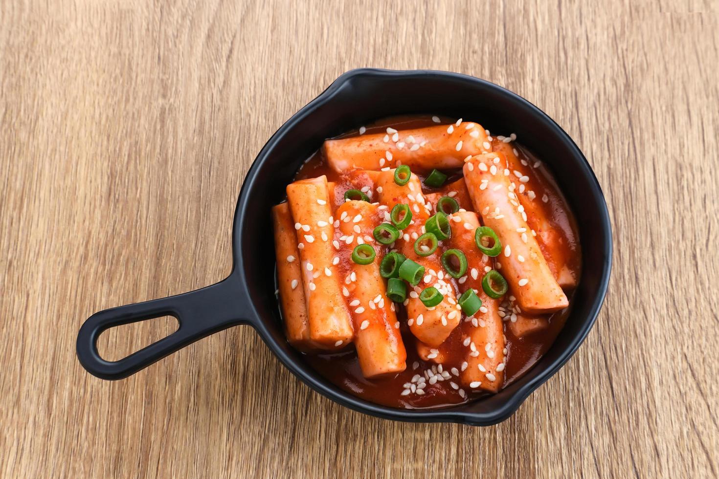 tteokbokki o topokki, palo de pastel de arroz salteado, popular comida callejera coreana con salsa gochujang picante y semillas de sésamo. foto