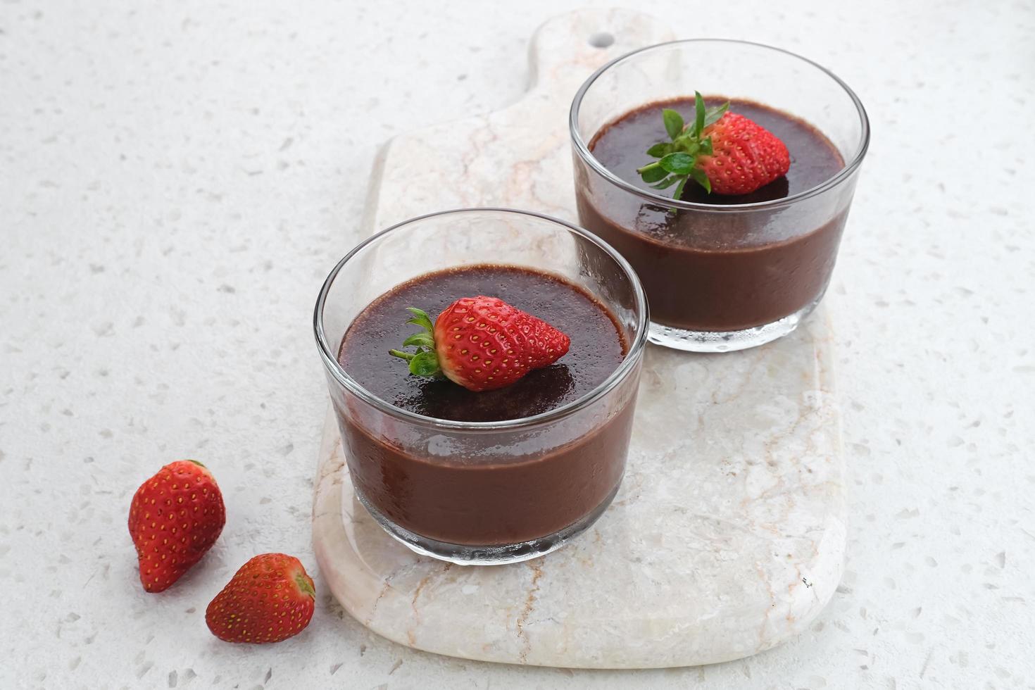 Chocolate pudding with strawberries in glass on white table. Selected focus. photo