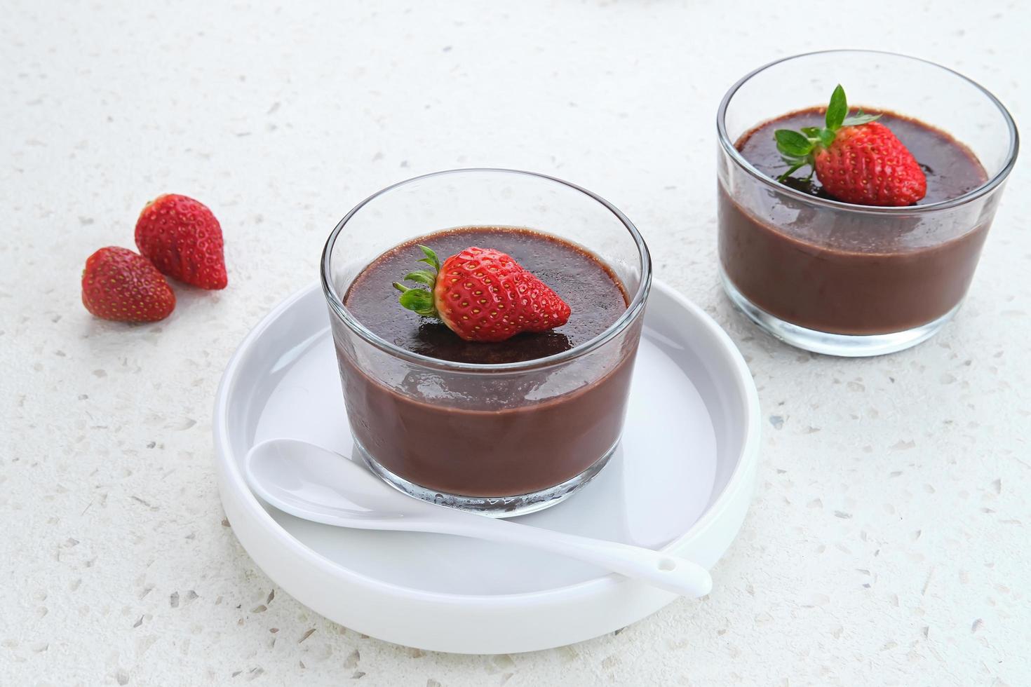 Chocolate pudding with strawberries in glass on white table. Selected focus. photo