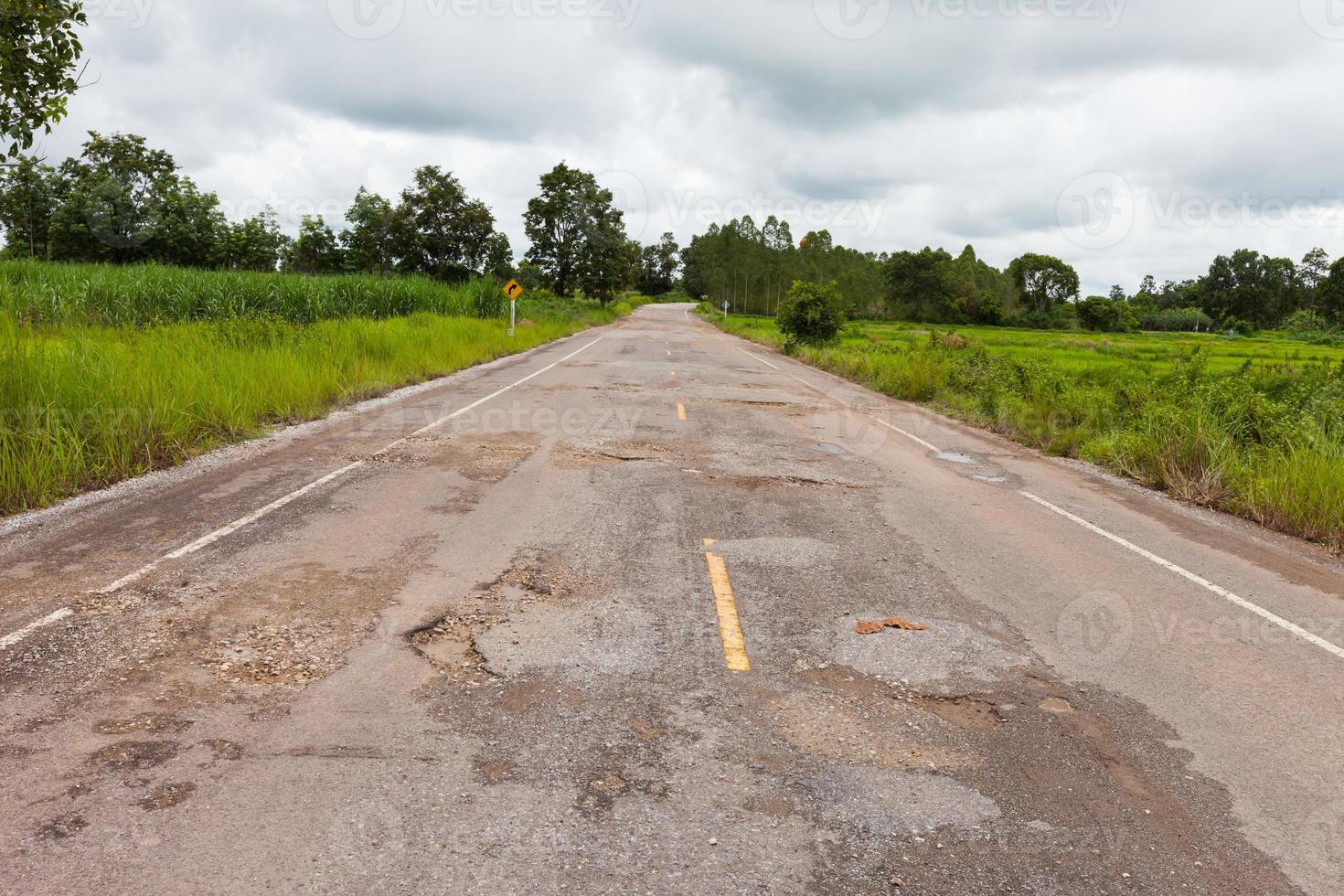 Damaged asphalt pavement road with potholes photo