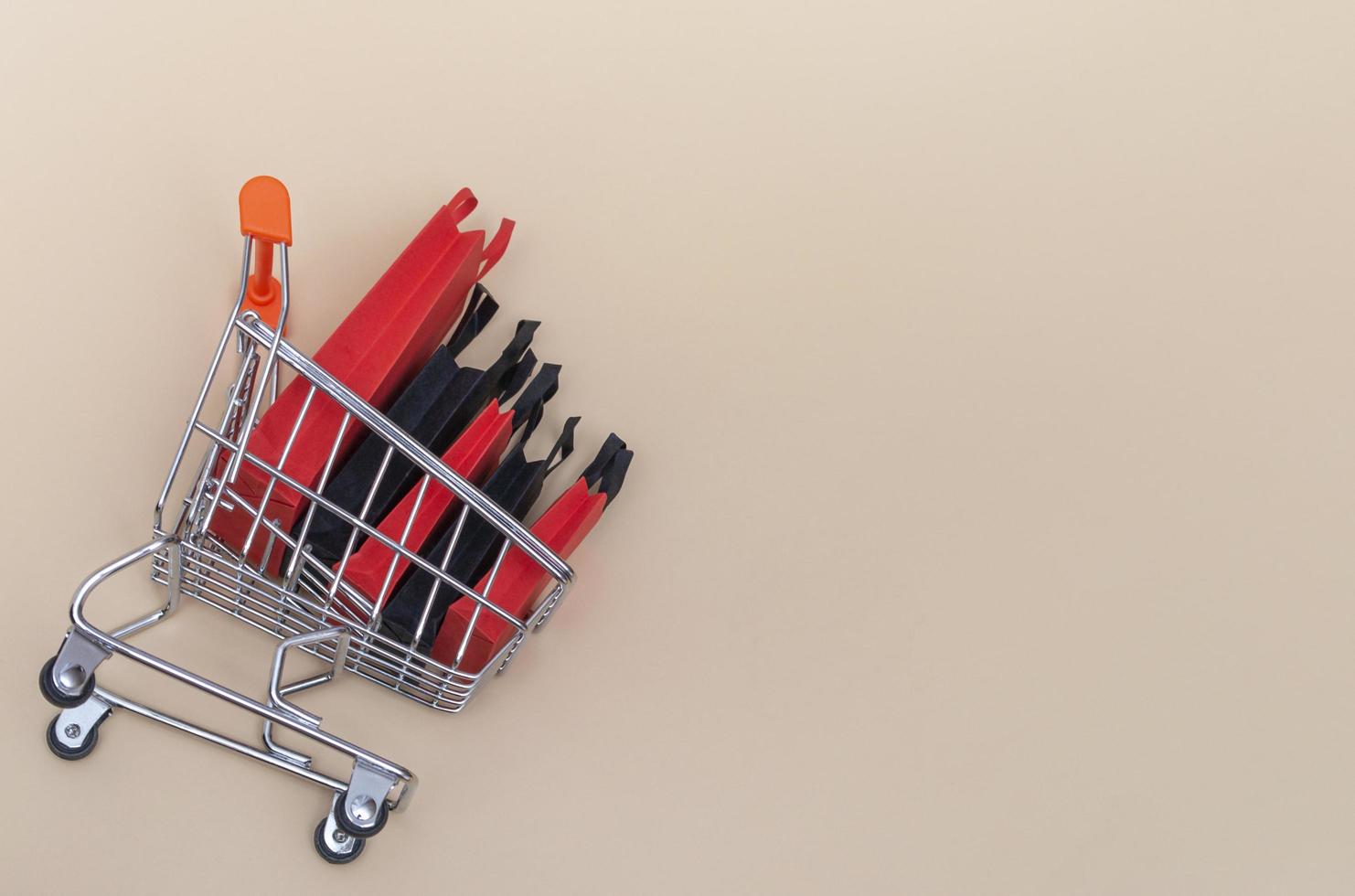 concepto de viernes negro, maqueta de bolsas de papel negras y rojas con carro sobre fondo de color. venta de viernes negro. foto