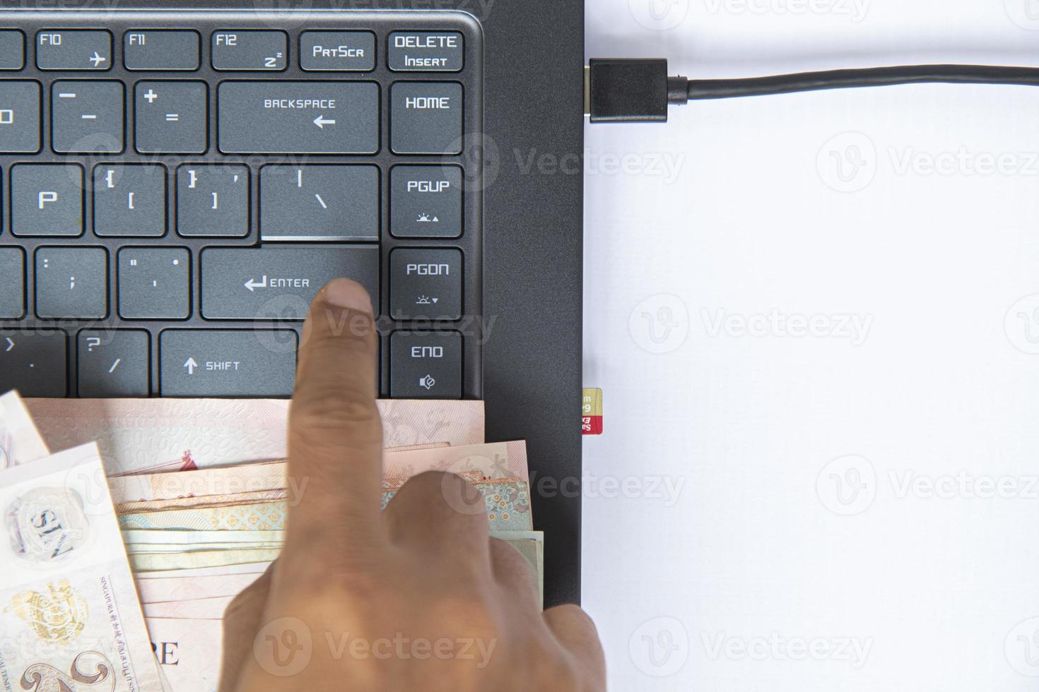 Top view black keyboard on notebook have banknote in hand, and a memory  card plugged into