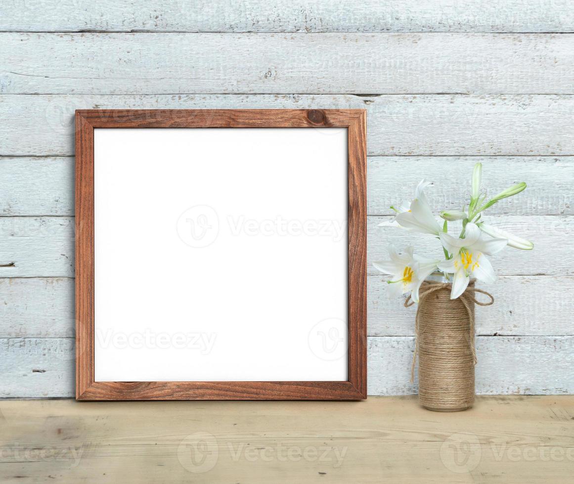 una maqueta cuadrada de madera vieja cerca de un ramo de lirios se encuentra sobre una mesa de madera sobre un fondo de madera pintada de blanco. estilo rústico, belleza sencilla. procesamiento 3d foto