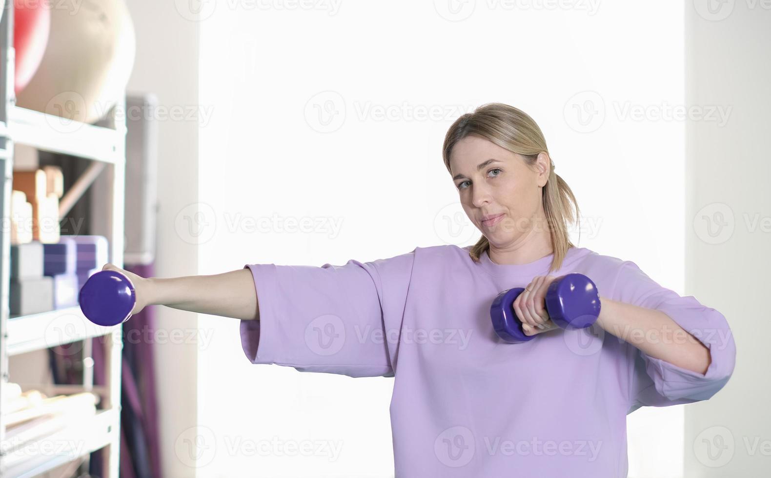 real woman working out with dumbbells at gym, alone training, workout routine, fitness club. photo