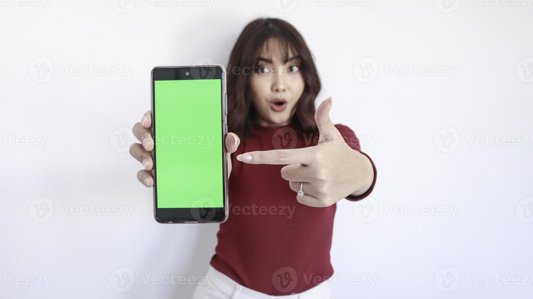 Wow and Shock Asian beautiful girl point on green screen phone with blurry background on face in white photo