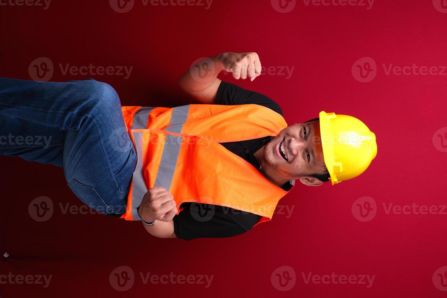 Happy excited and smiling young Asian man worker raising his arm up to celebrate success or achievement. photo