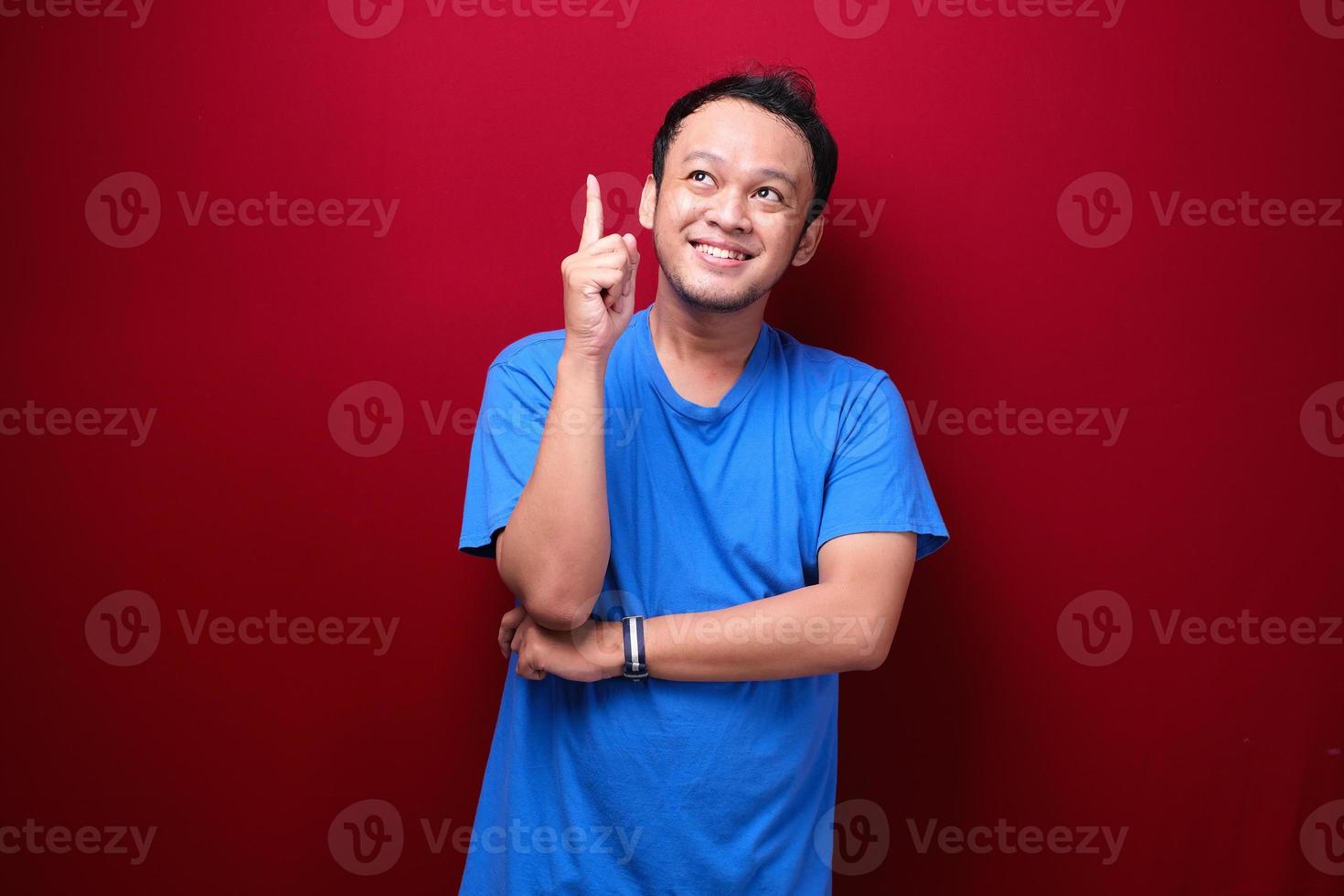 Happy young asian man is with with hand point above on empty space photo