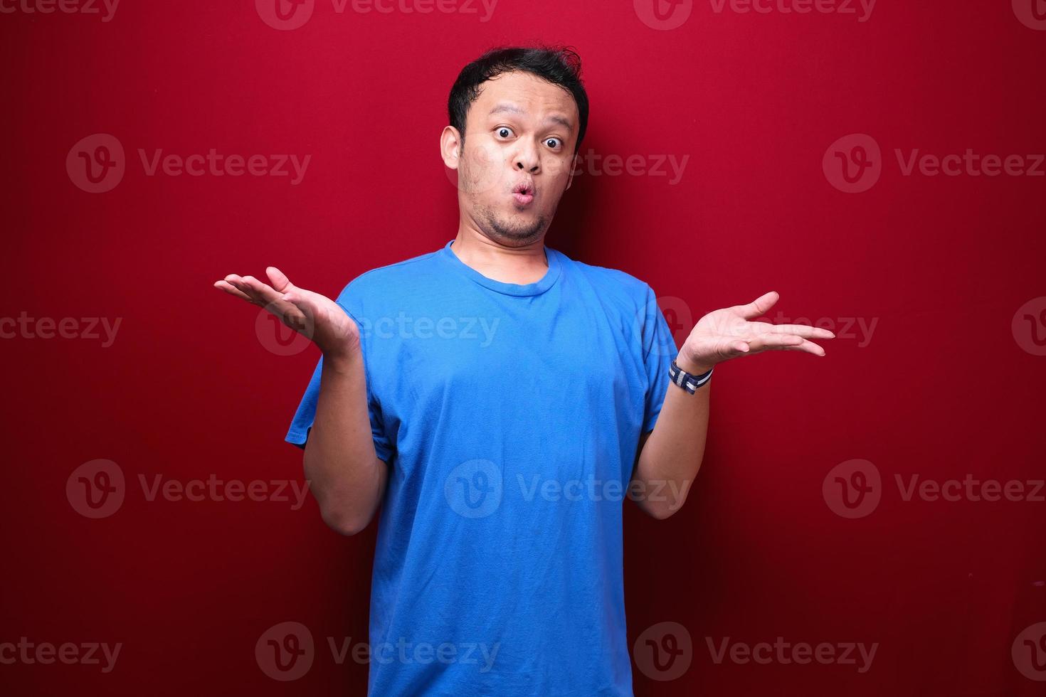 Young asian man is surprised and shouting wow with pointing right with his hand isolated on red background. photo