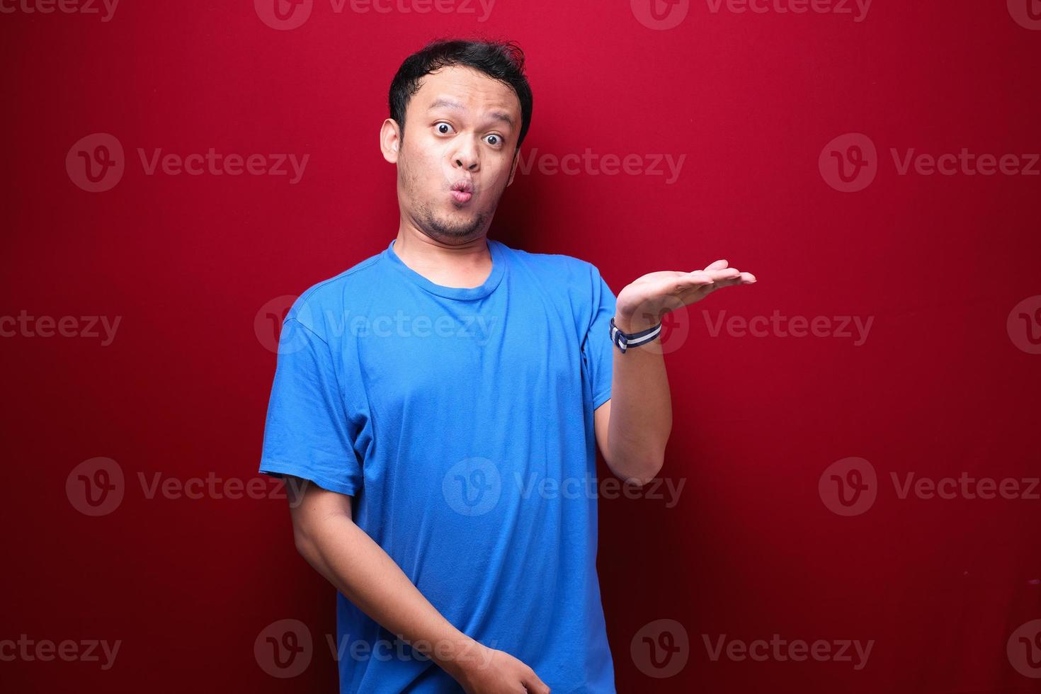 Young asian man is surprised and shouting wow with pointing right with his hand isolated on red background. photo