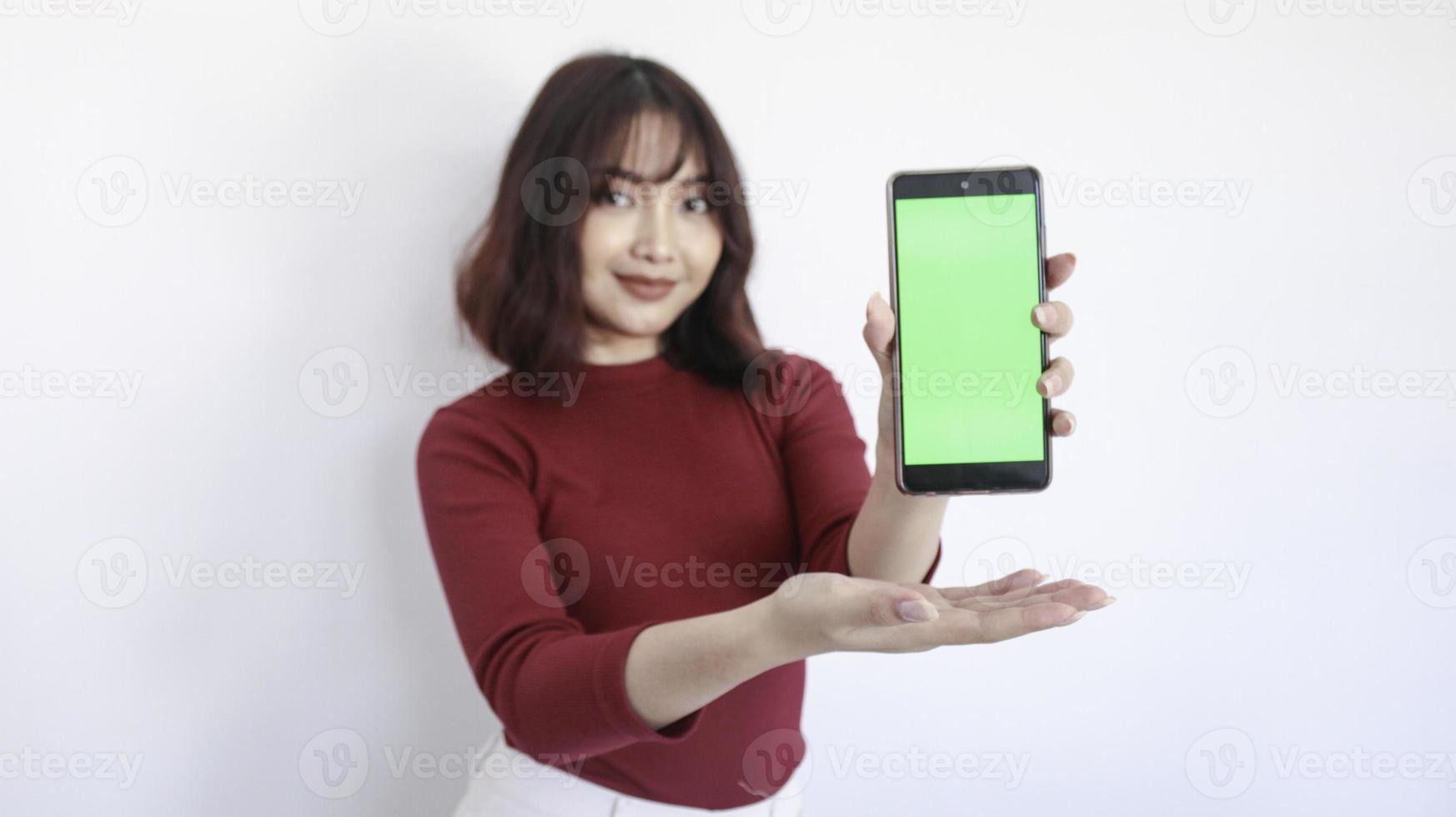 Asian beautiful girl point on green screen phone with with blurry background on face in white background photo