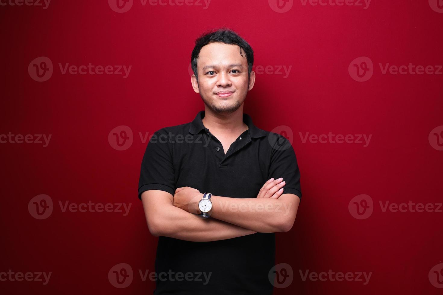 Portrait of smiling young asian man wearing black shirt isolated on red. photo