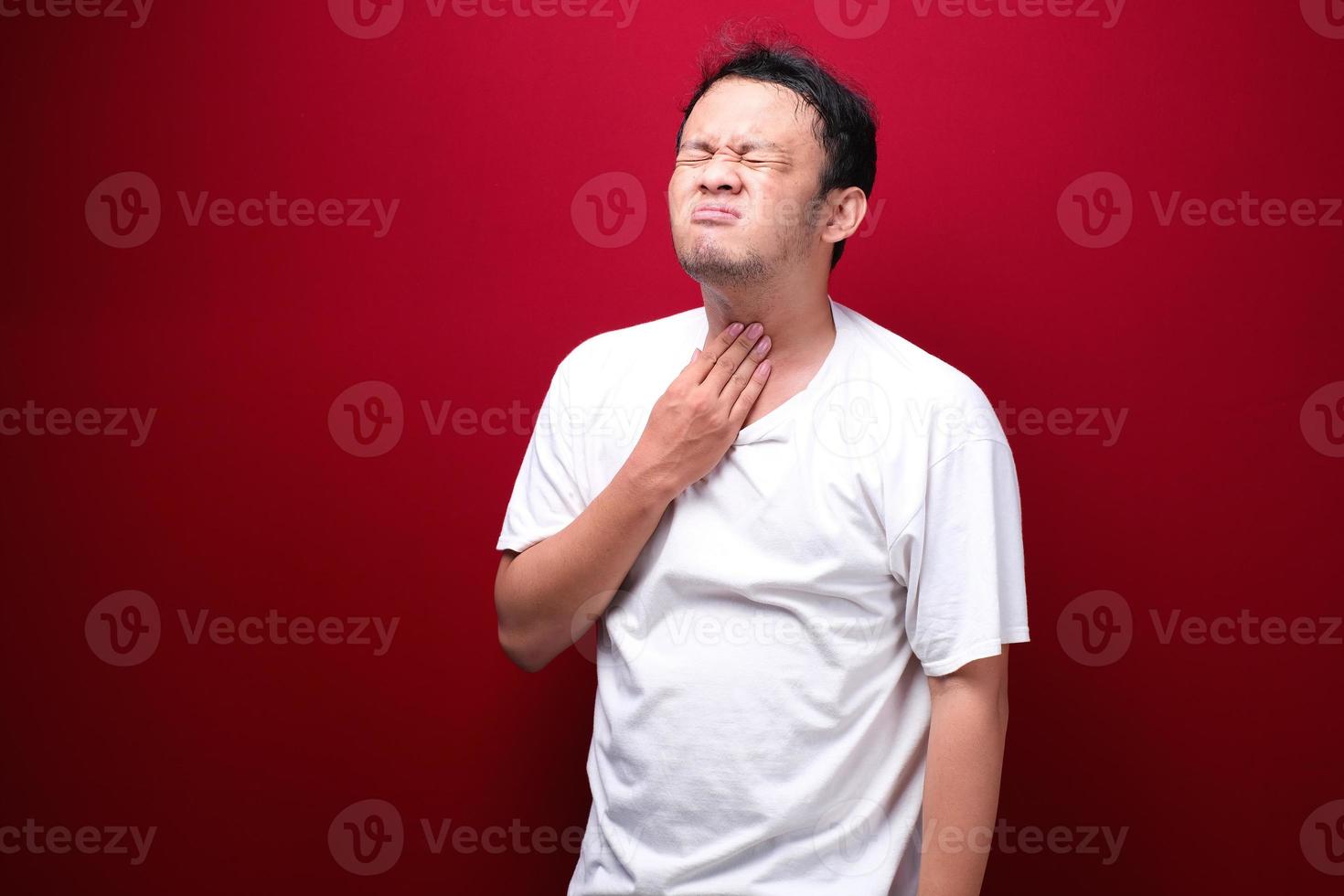 Sore throat of young asian man in red background photo