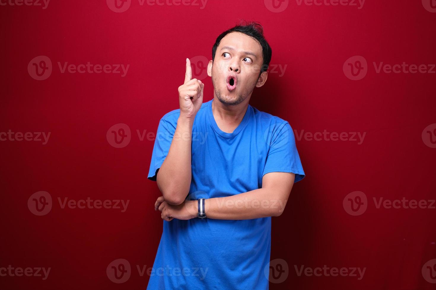 Shock Young asian man is surprised and shouting wow with pointing above with his hand isolated on red background. photo