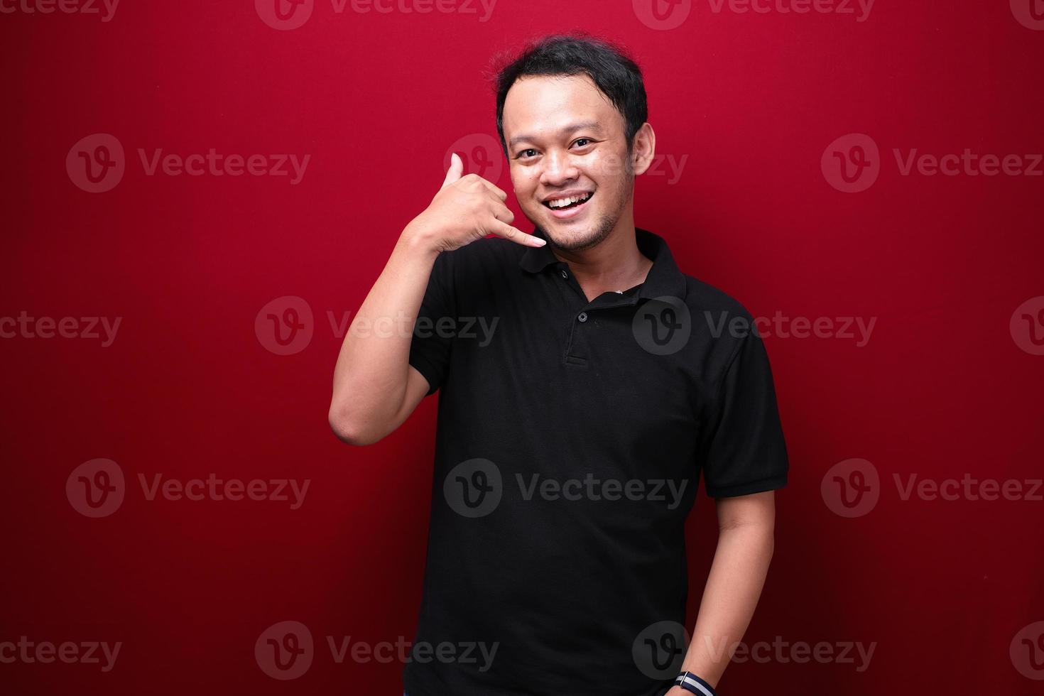 Smiling young asian man with talk or call gesture hand photo