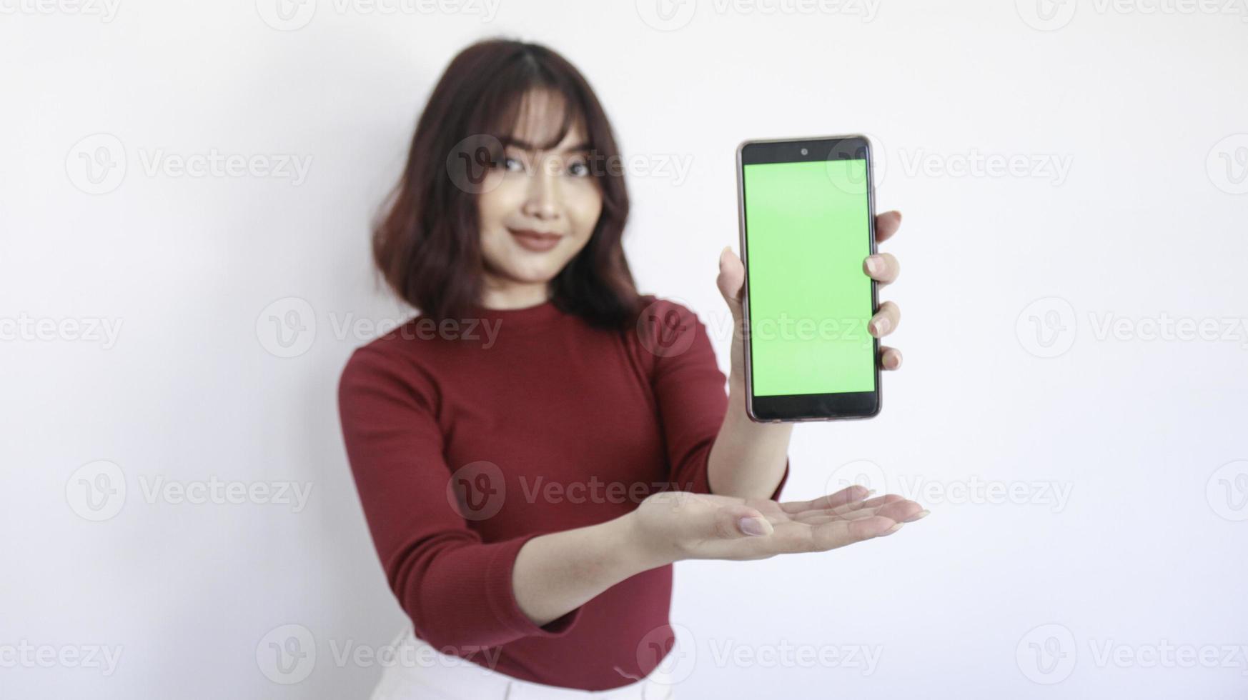 Asian beautiful girl point on green screen phone with with blurry background on face in white background photo