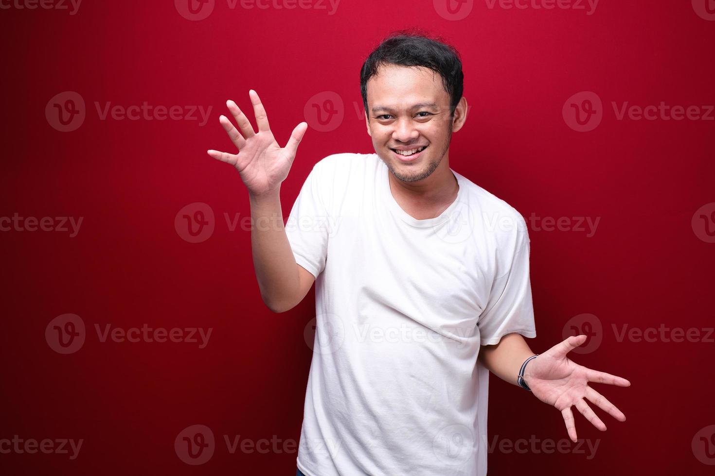 joven asiático es feliz y sonriente con gesto de mano abierta foto