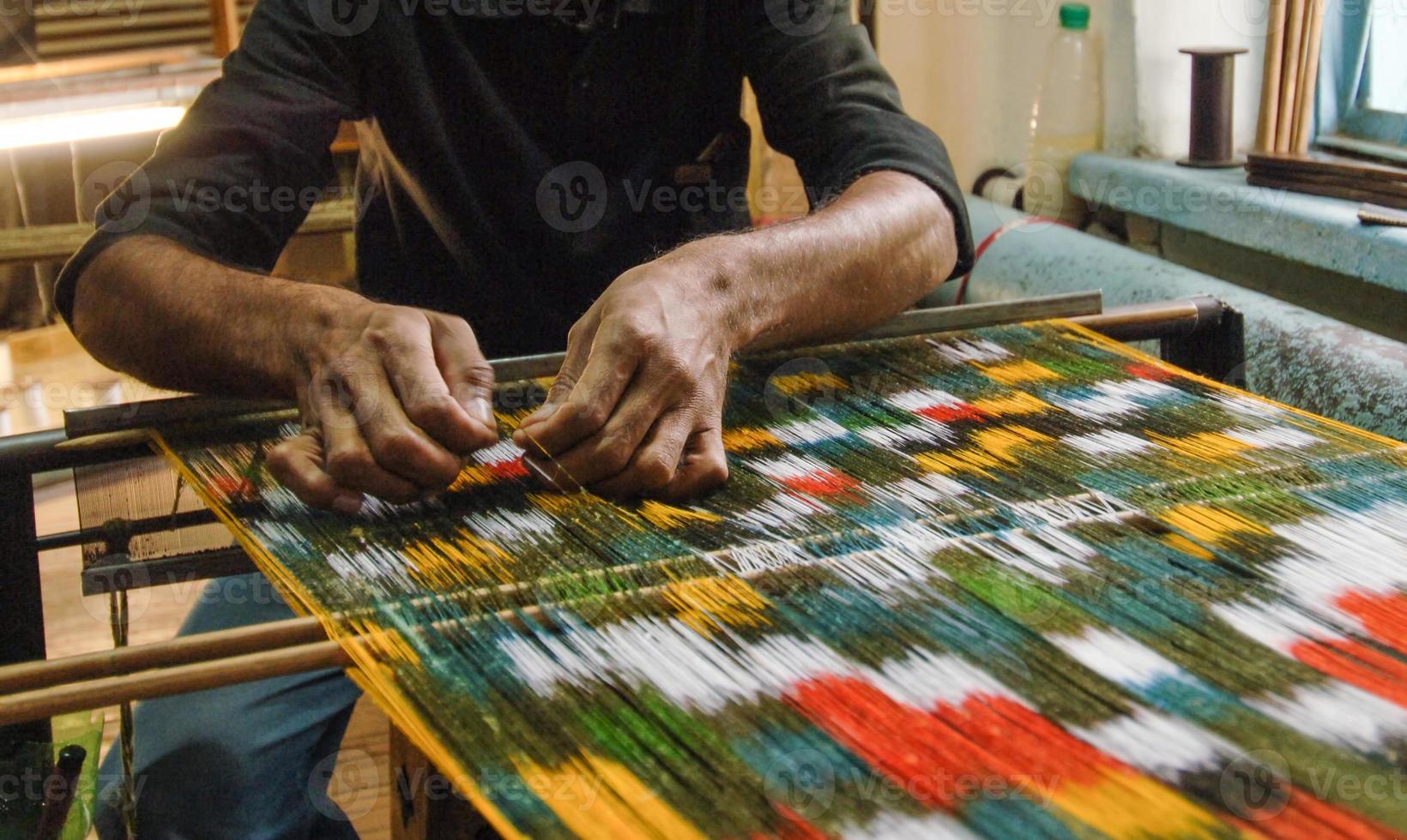 tejido y fabricación de alfombras artesanales. manos del hombre detrás de un telar foto