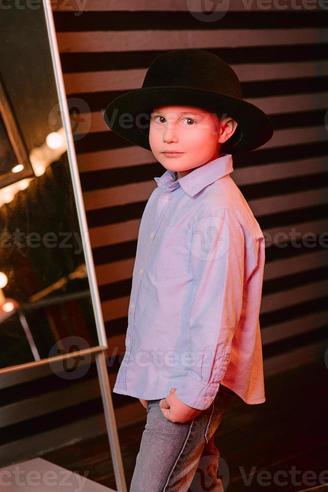 Stylish portrait of young boy in black hat in photo studio