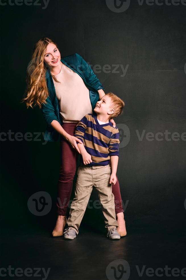 portrait of stylish cute little boy with beautiful mom in photo studio