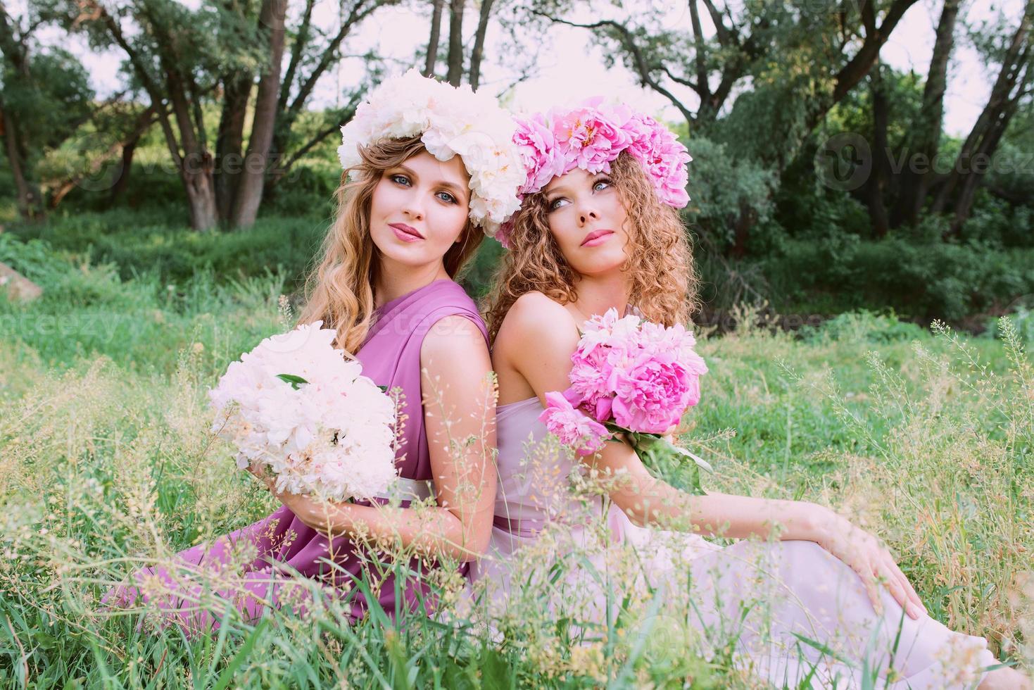 two caucasian beautiful woman with a wreath of pink peonies. Spring, blossom, fairy concept photo
