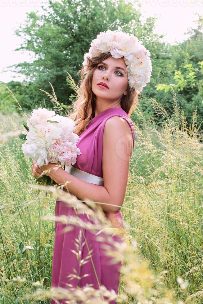 hermosa mujer caucásica con una corona de peonías en la cabeza. primavera, flor, concepto de hadas foto