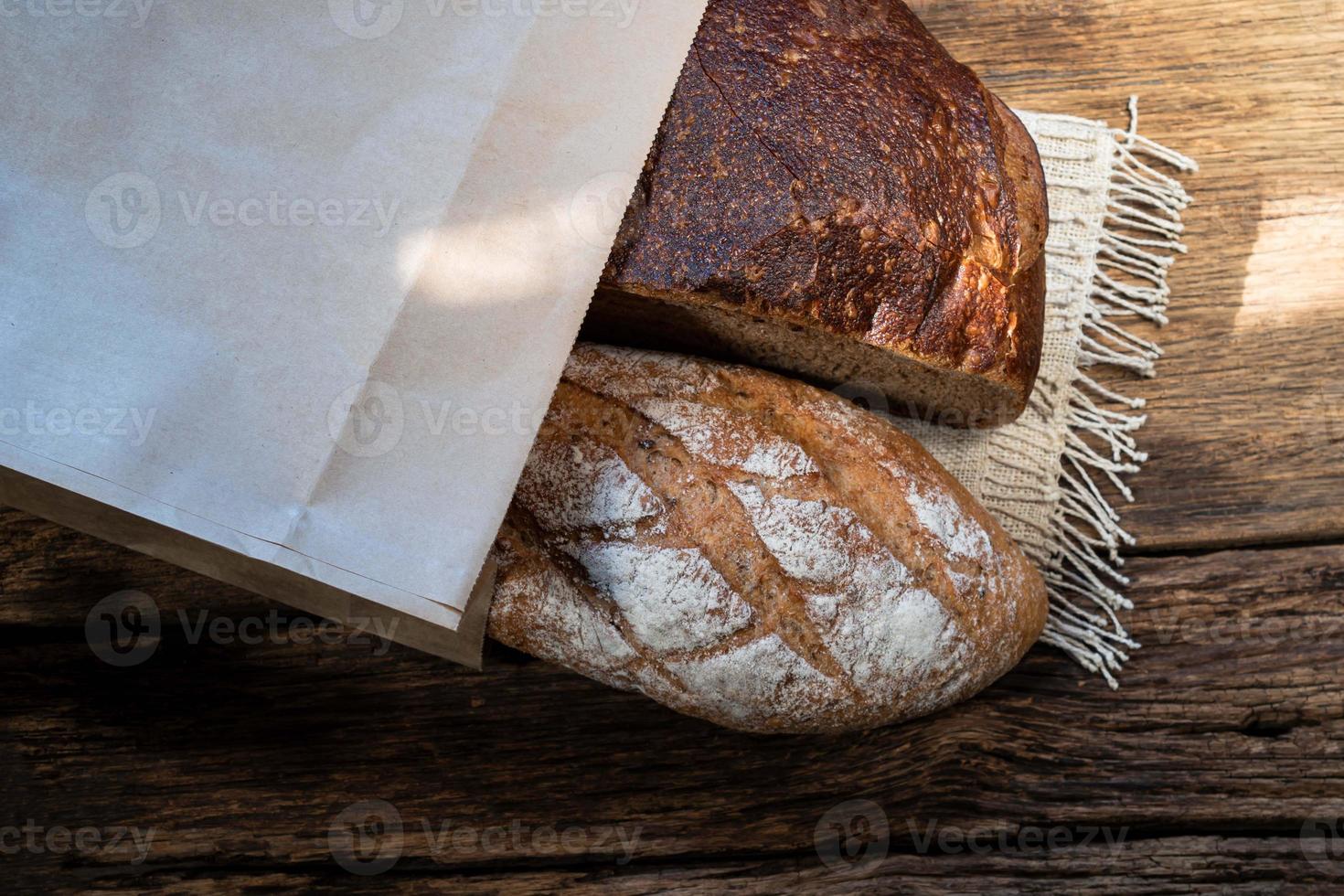 different bread rye and baguette in bag isolated on wood photo