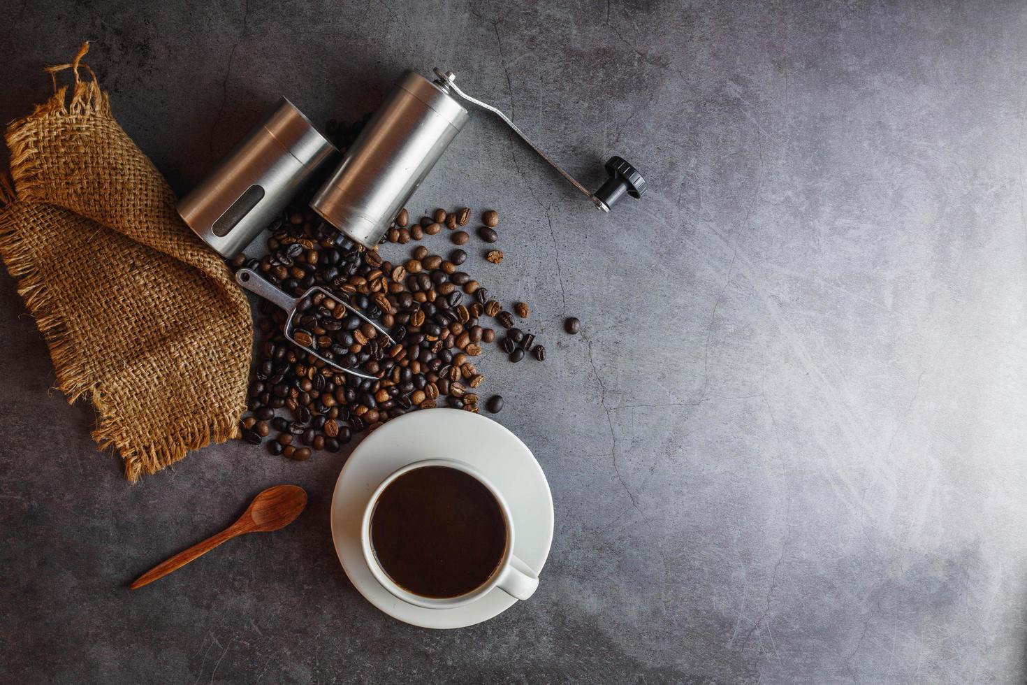 Hand coffee grinder and coffee beans and coffee cup on table. photo