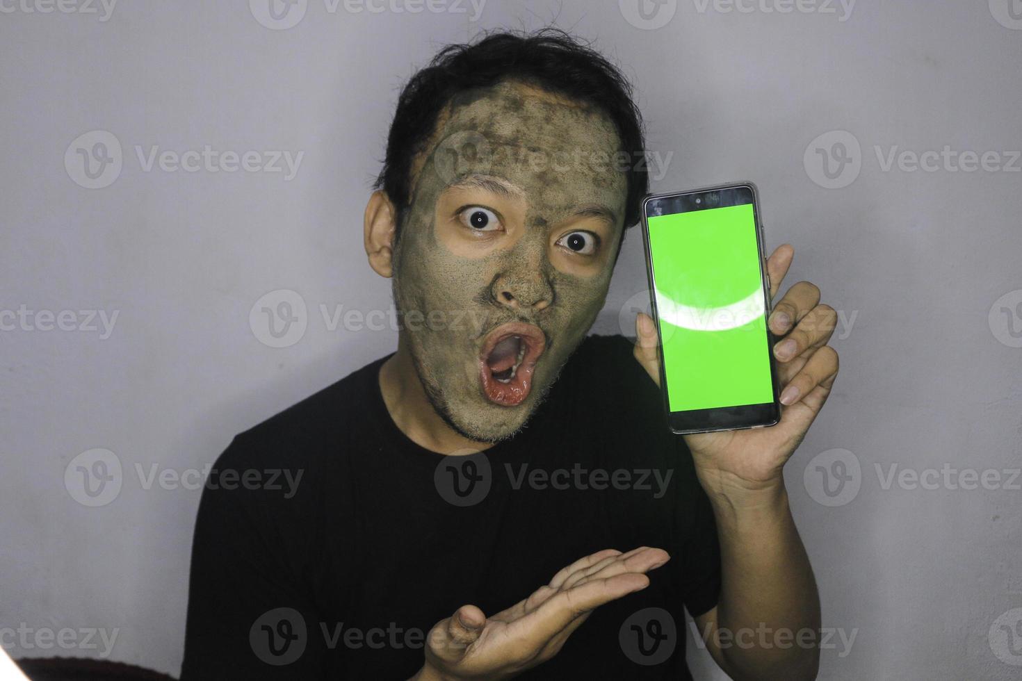 Shock Asian Man showing blank screen when he use beauty face mask photo