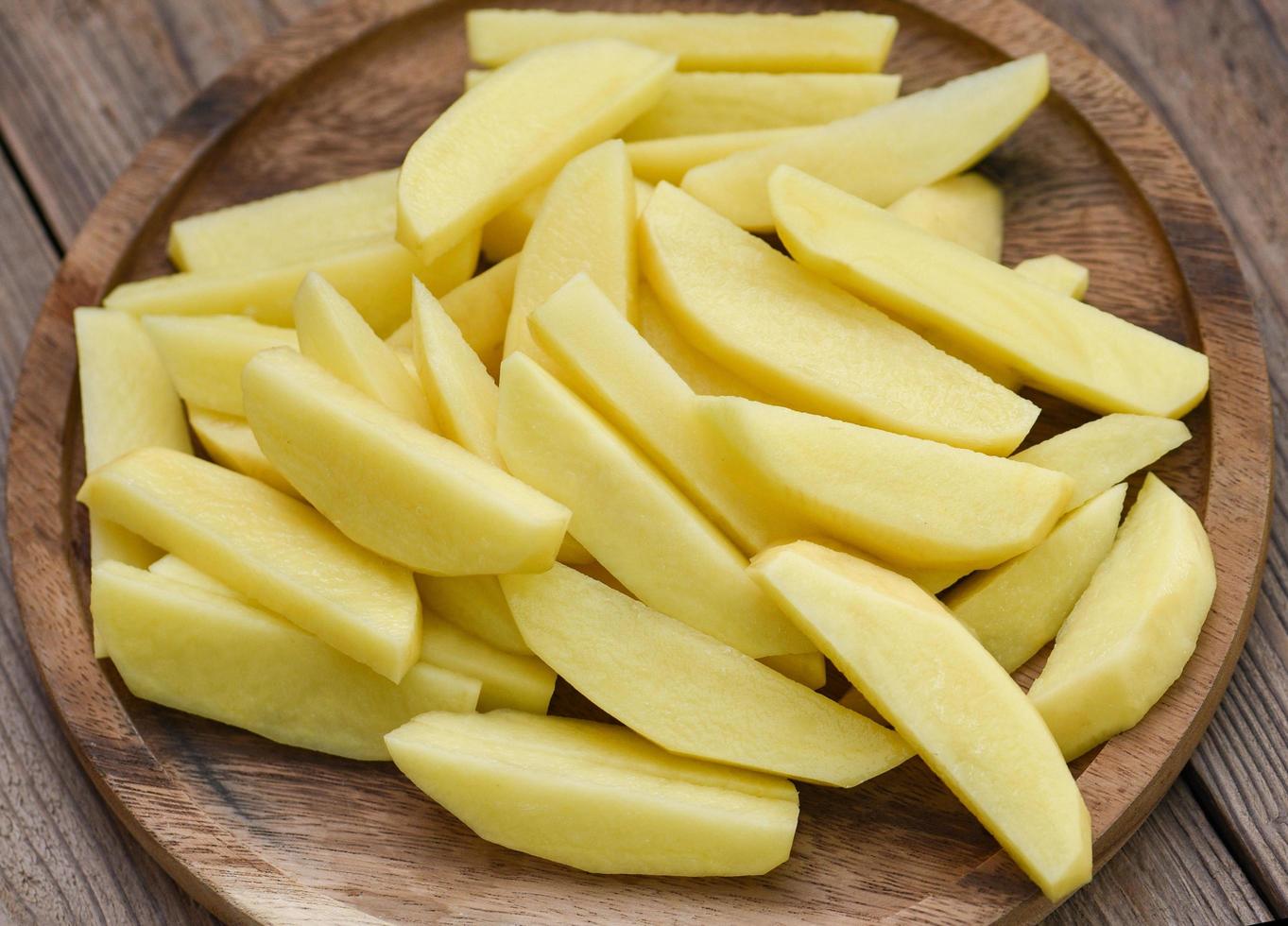 chopped potatoes for cooked food on wooden bcakground, fresh raw potato wedges photo