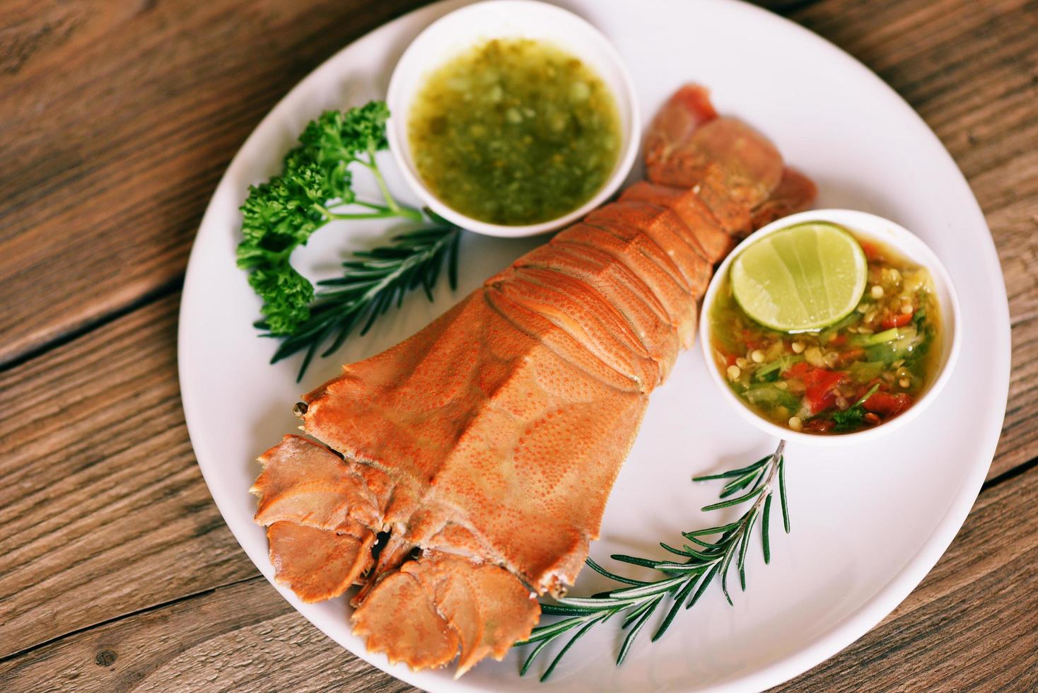 camarones de langosta de cabeza plana servidos en un plato blanco y salsa de marisco, langosta fresca de zapatilla cocinada hervida con romero de perejil en el restaurante de mariscos - vista superior foto