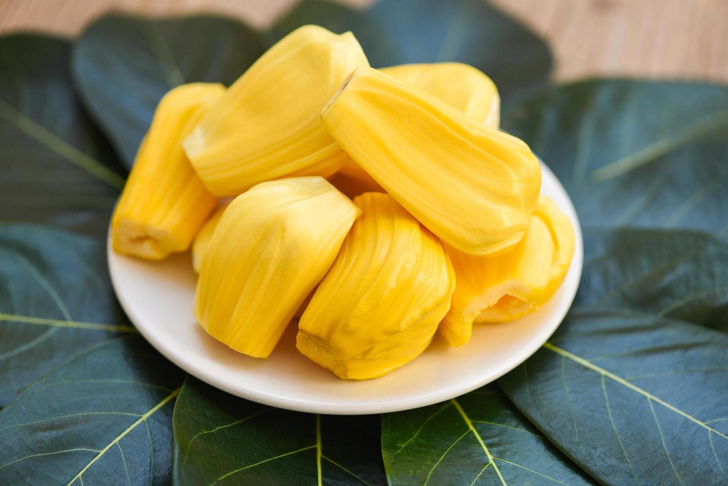 Ripe jackfruit peeled tropical fruit fresh from jackfruit tree, Jackfruit on white plate and green leaf background photo