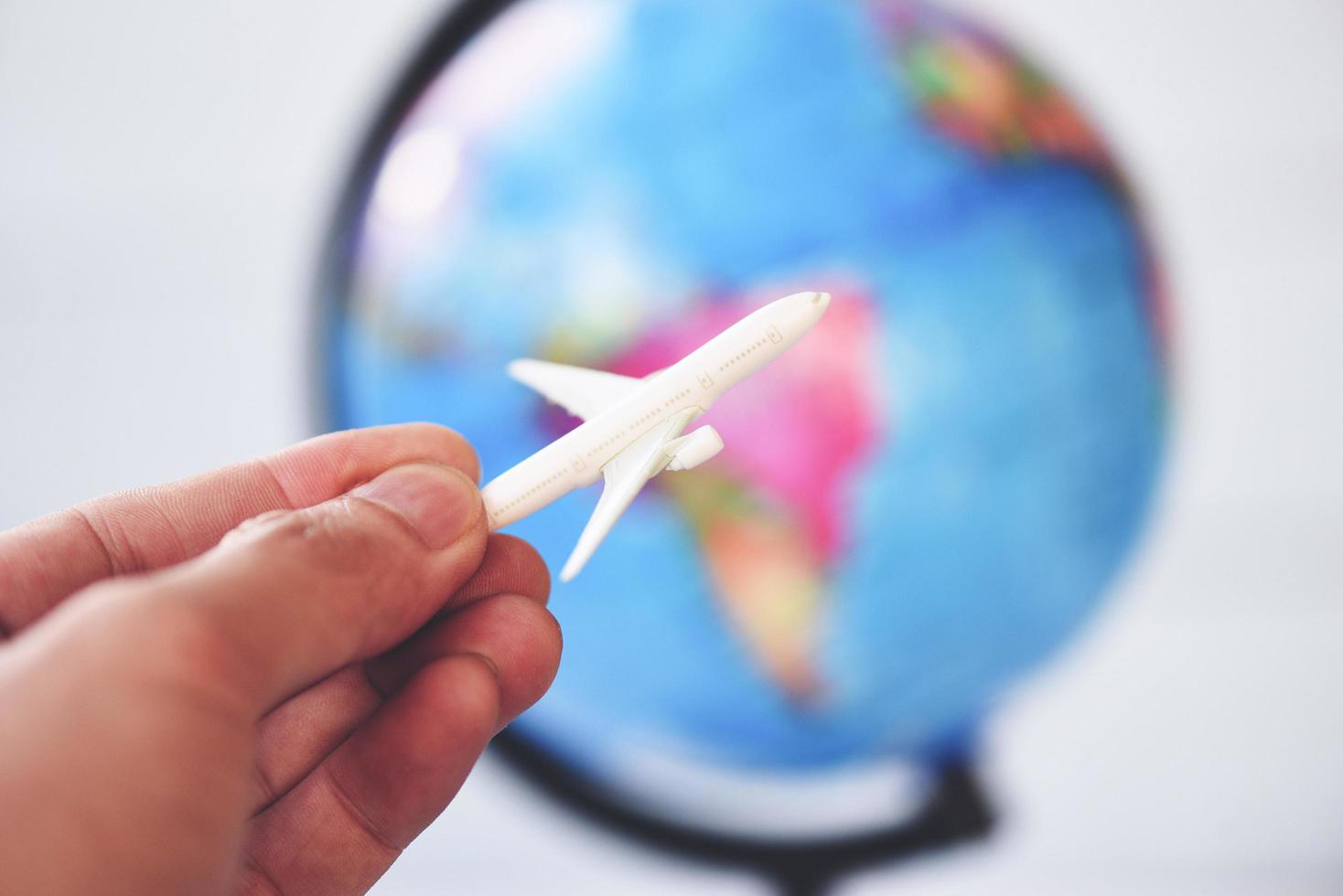 Business man holding airliner aircraft plane on world globe background - worldwide travel concept photo