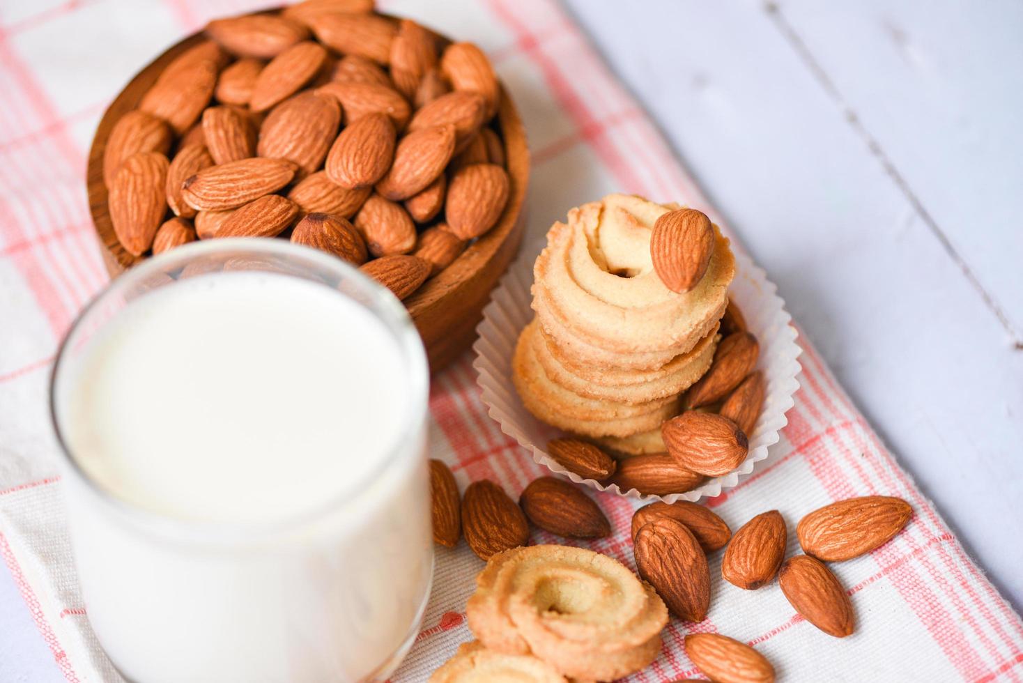 vaso de leche de almendras y galleta para el desayuno comida saludable - nueces de almendras sobre fondo de tazón de madera foto