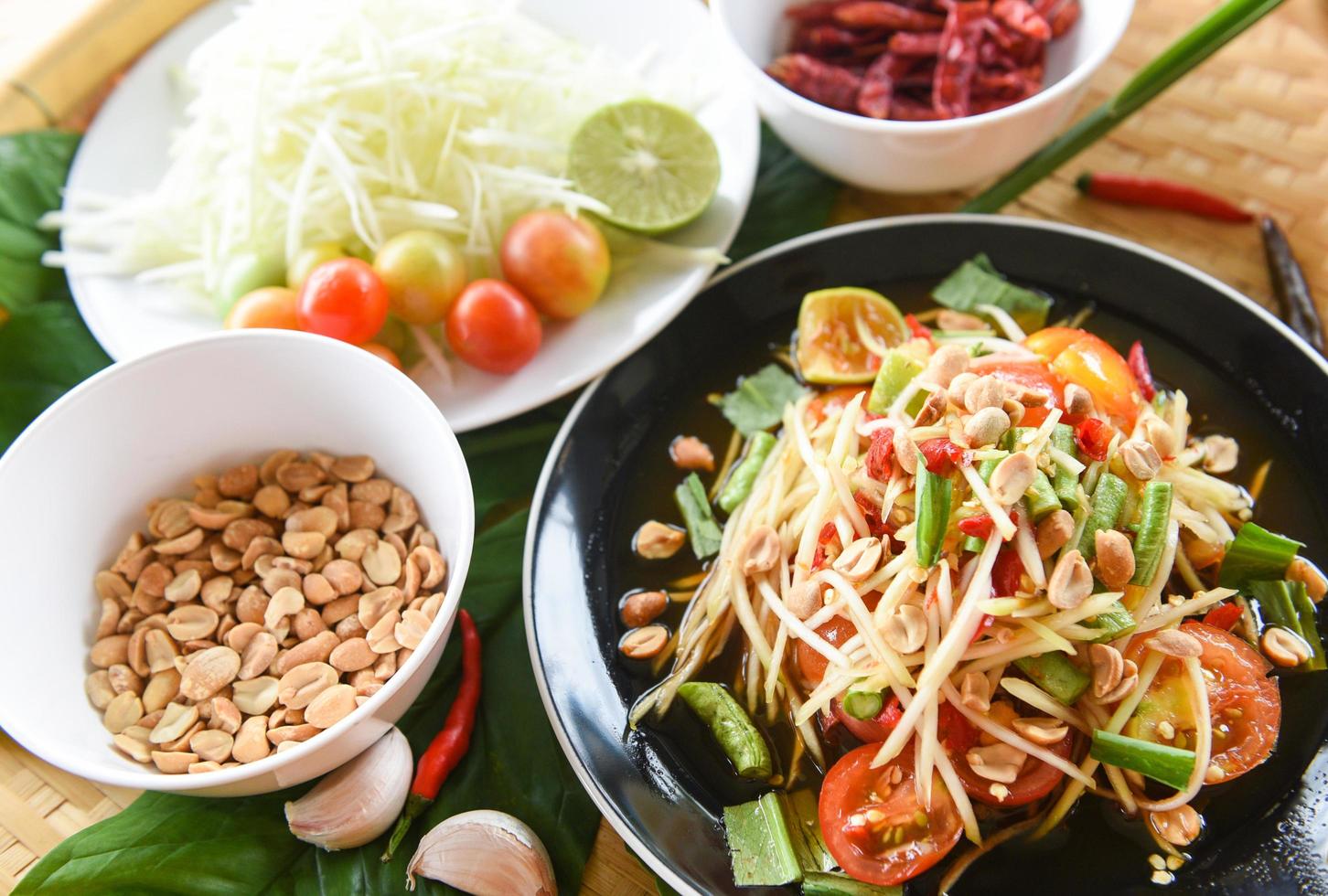 vista superior de la comida tailandesa - ensalada de papaya picante con hierbas de frijol de un metro y especias ingredientes chile tomate cacahuete ajo servido en la mesa foto