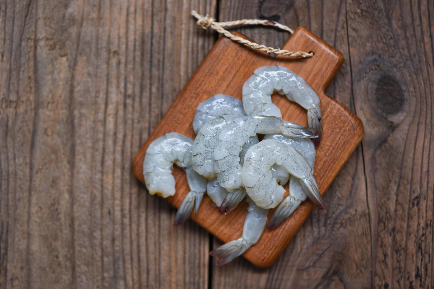 fresh shrimps or prawns , Seafood shelfish for cooking - raw shrimp on wooden cutting board background photo