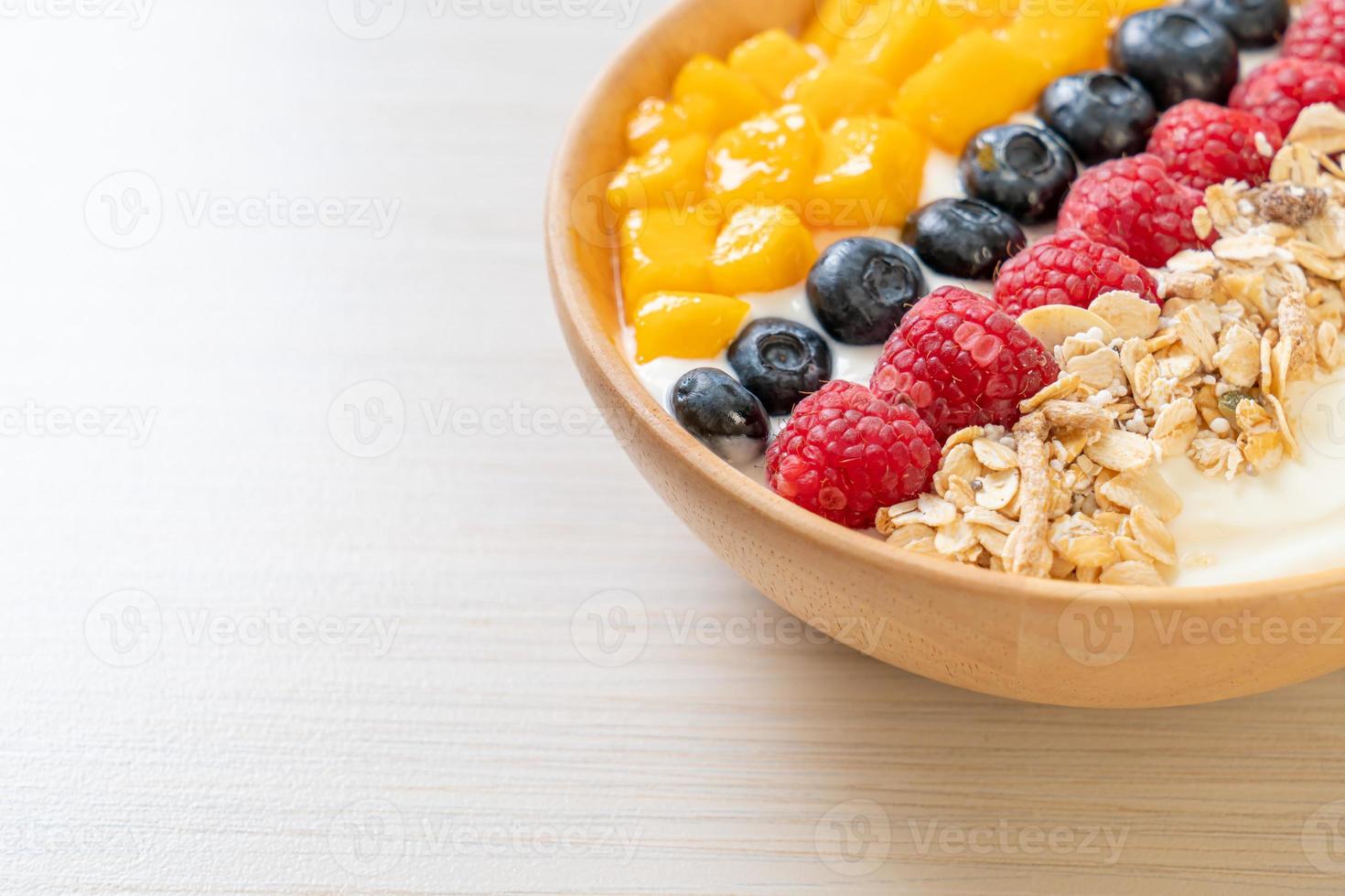 tazón de yogur casero con frambuesa, arándano, mango y granola foto