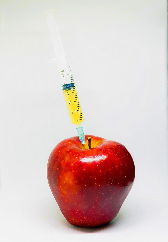 Apple with syringes. Genetically Modified Organism photo