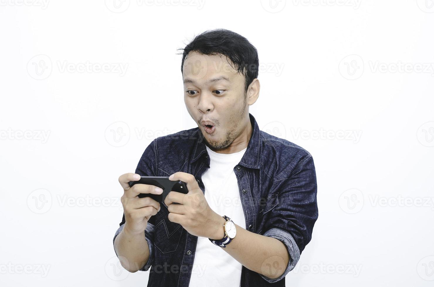 Wow face of Young Asian man shocked and surprised when he play on smartphone. photo
