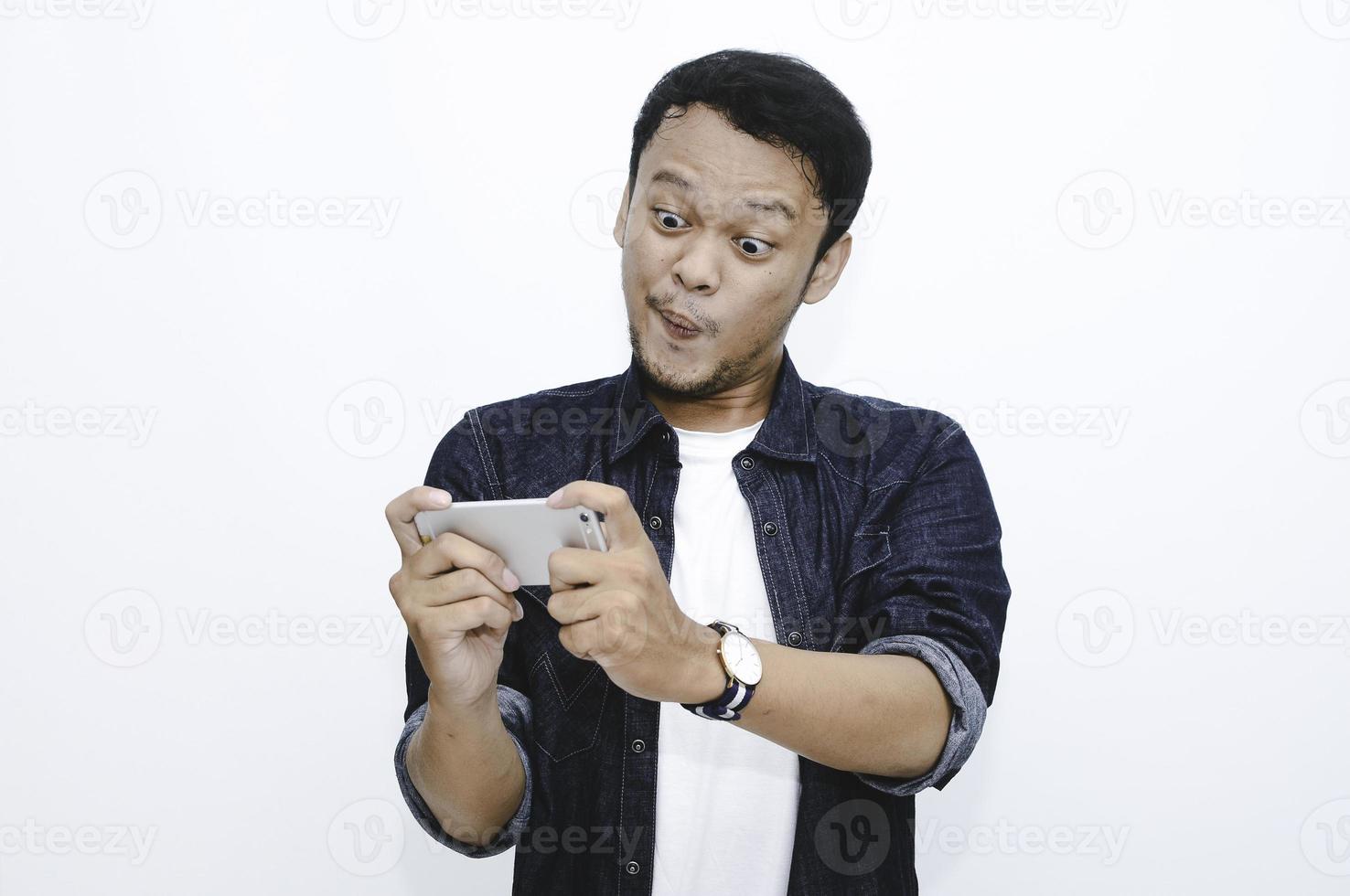 Wow face of Young Asian man shocked and surprised when he play on smartphone. photo