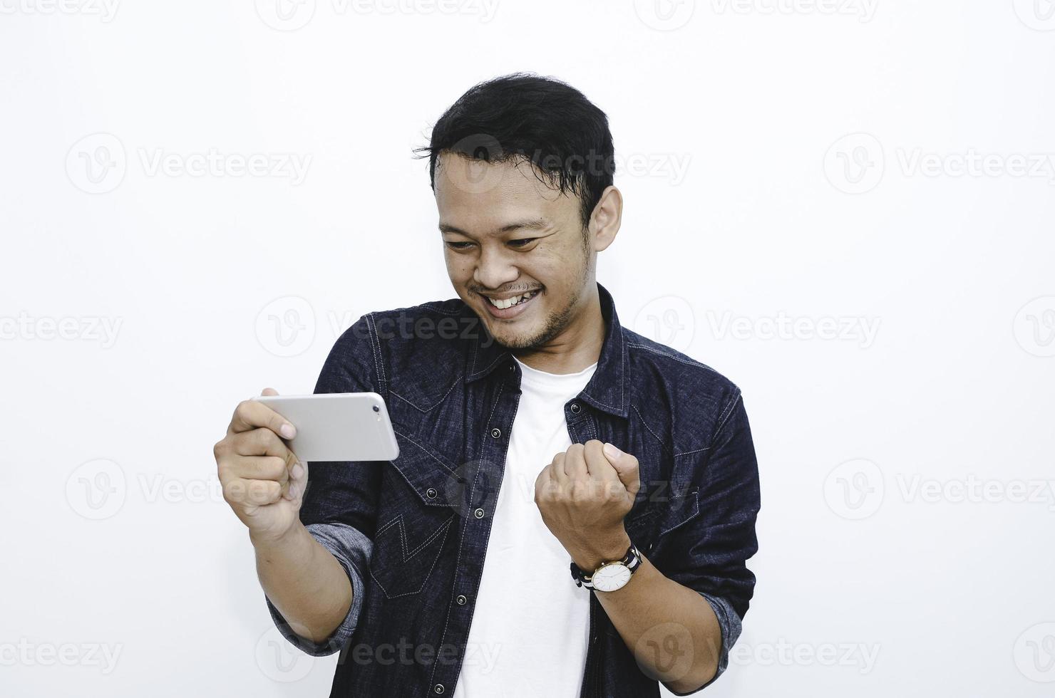 Smile and happy face of Young Asian man when playing game at phone in hand. photo