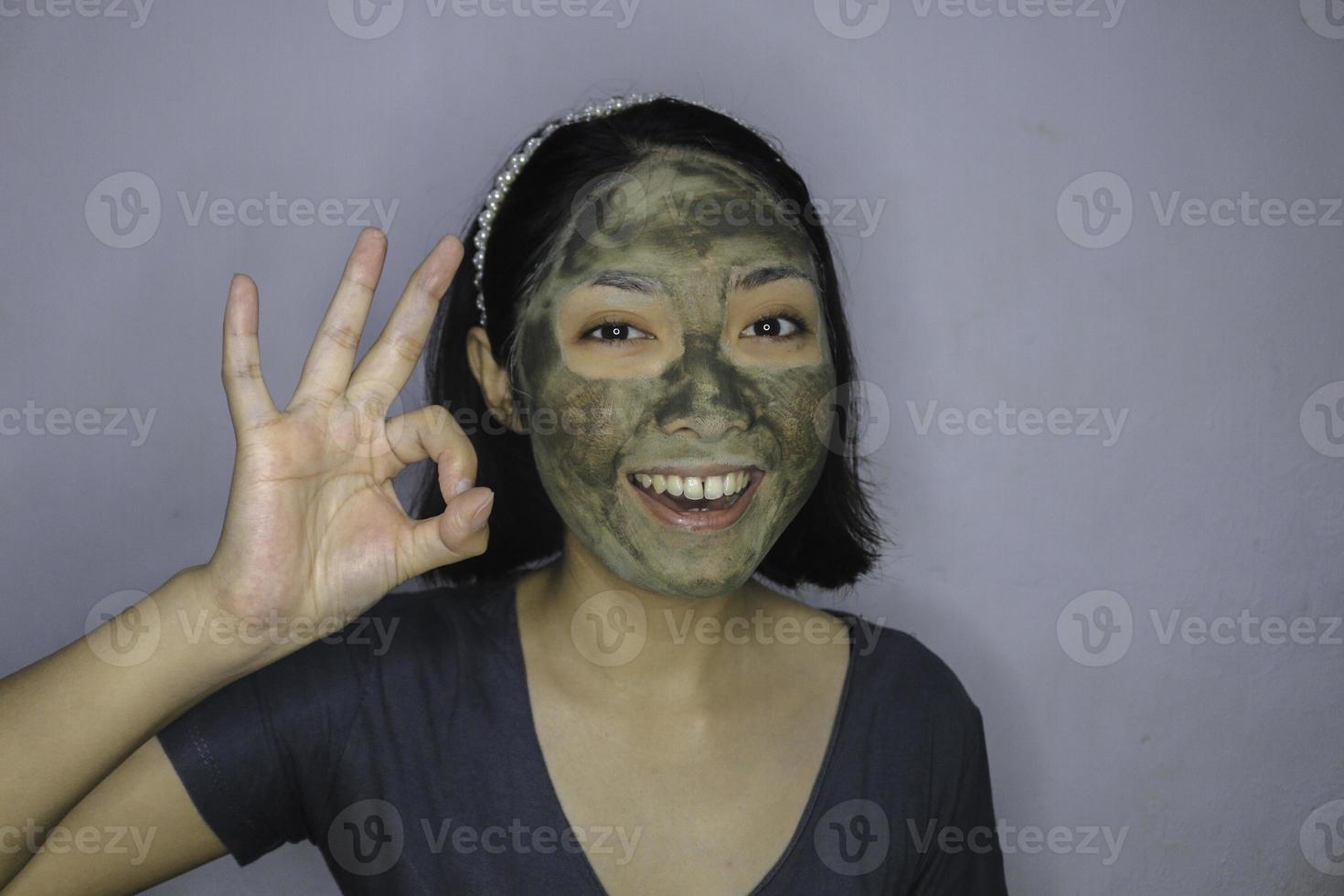 sonríe a las mujeres asiáticas sonriendo cuando usa una máscara facial de belleza foto