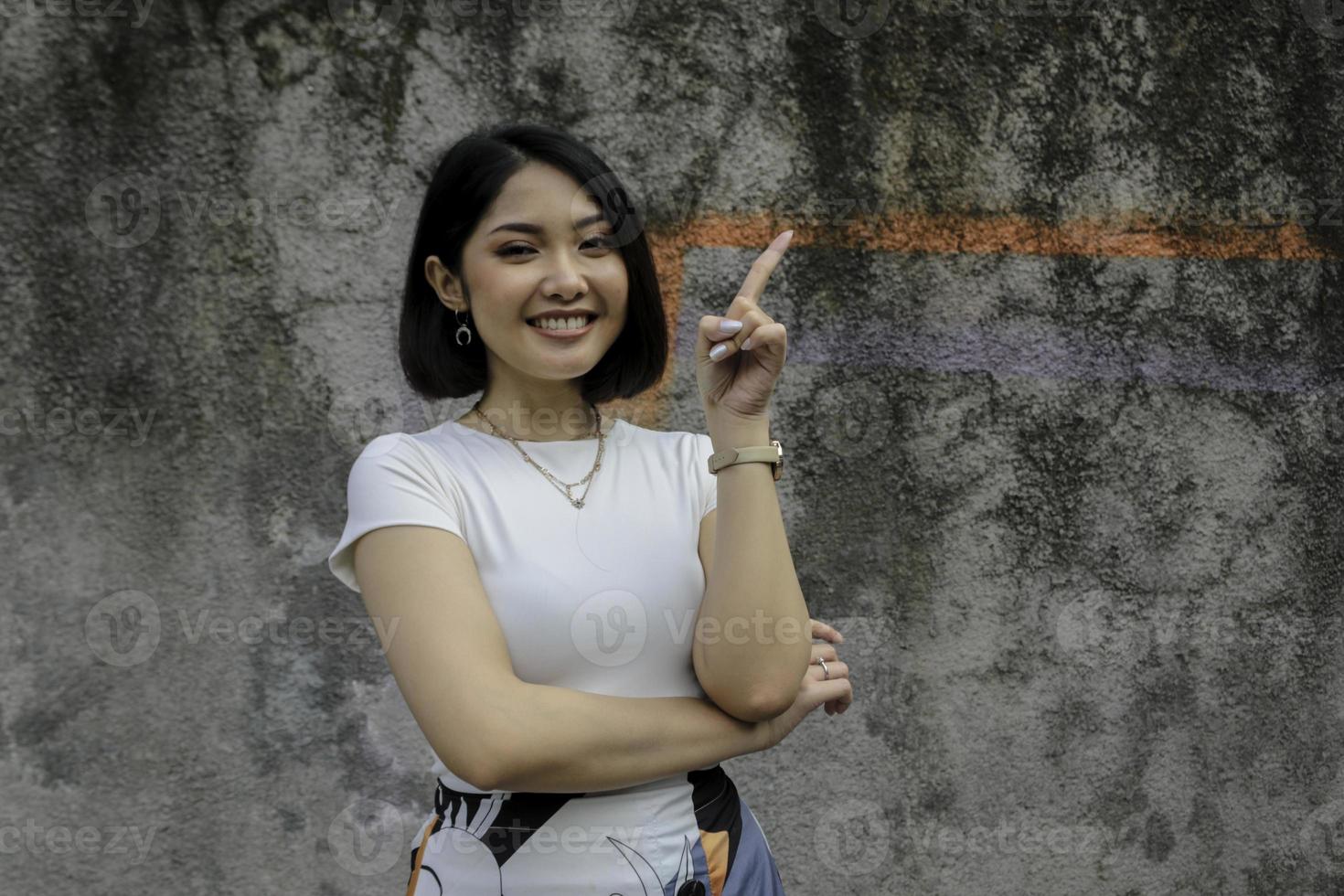 Happy and smile face with smile of young Asian girl with hand point on empty space. photo