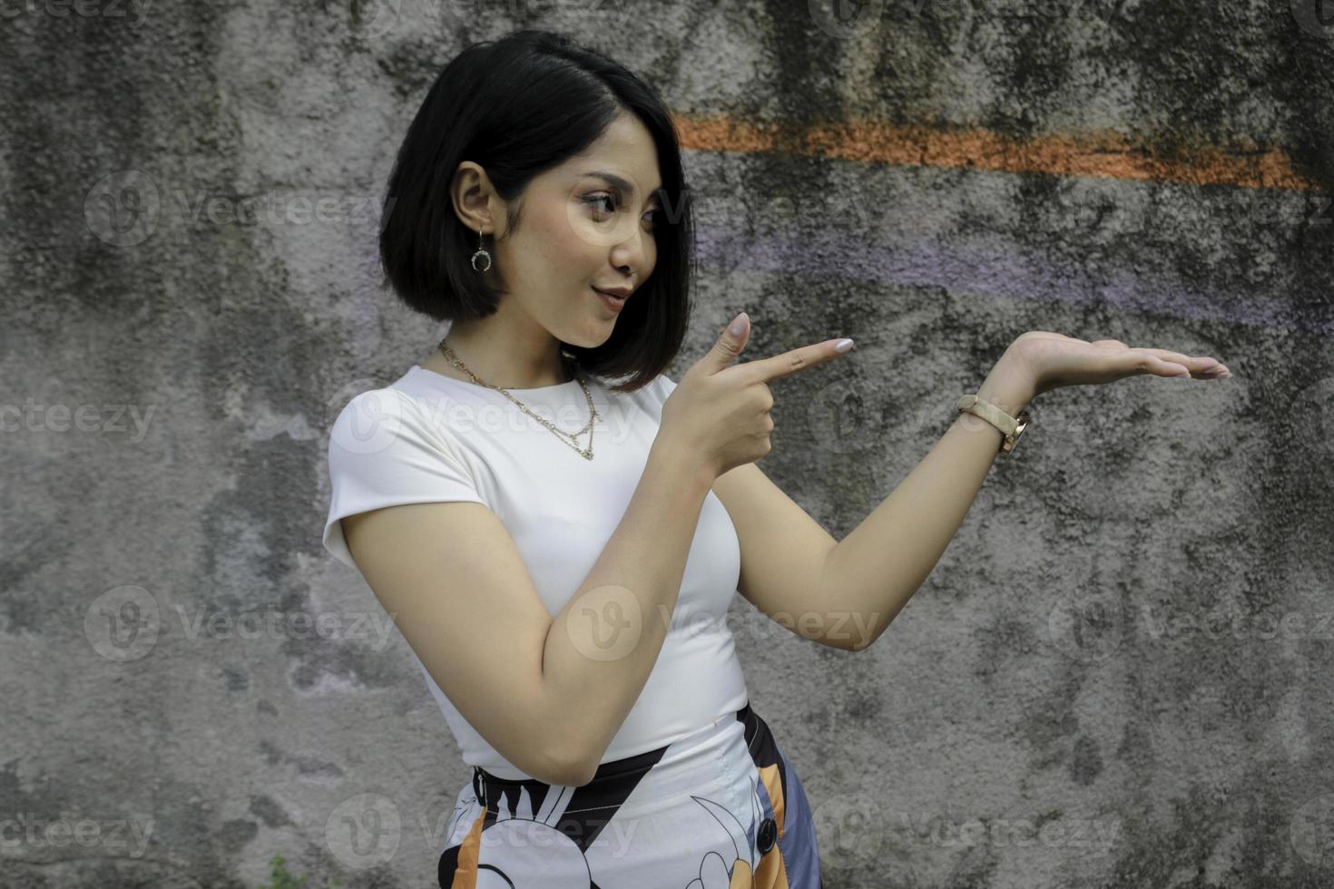 Happy and smile face with smile of young Asian girl with hand point on empty space. photo