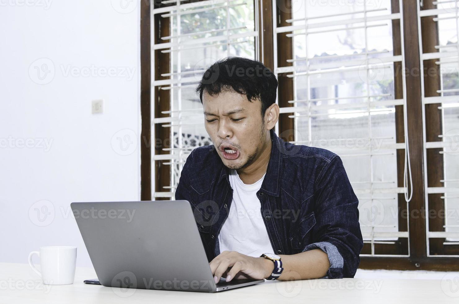 Young Asian man feeling stress and sad when work laptop on table. photo