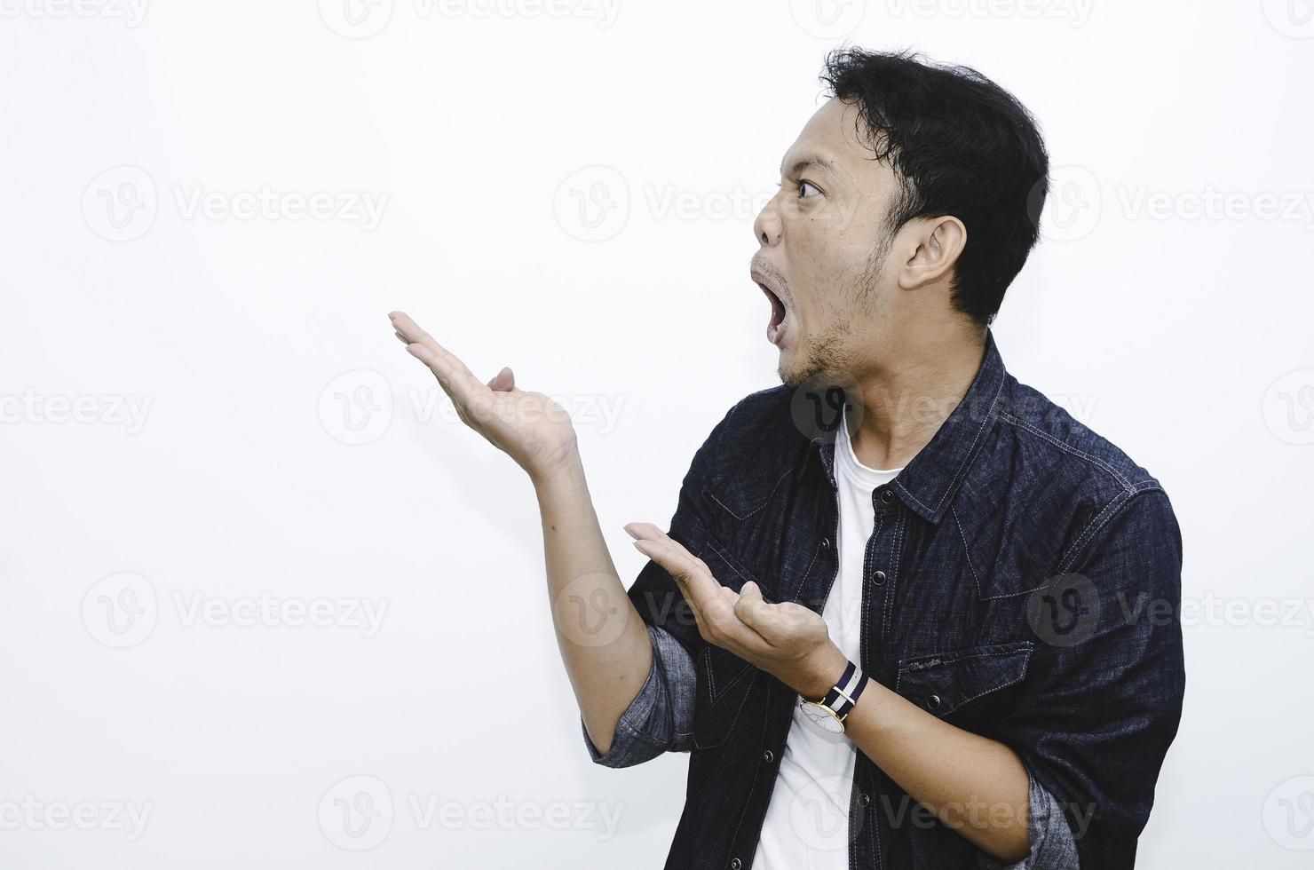 Young asian man is surprised and shouting wow with pointing right with his hand isolated on gray background. photo