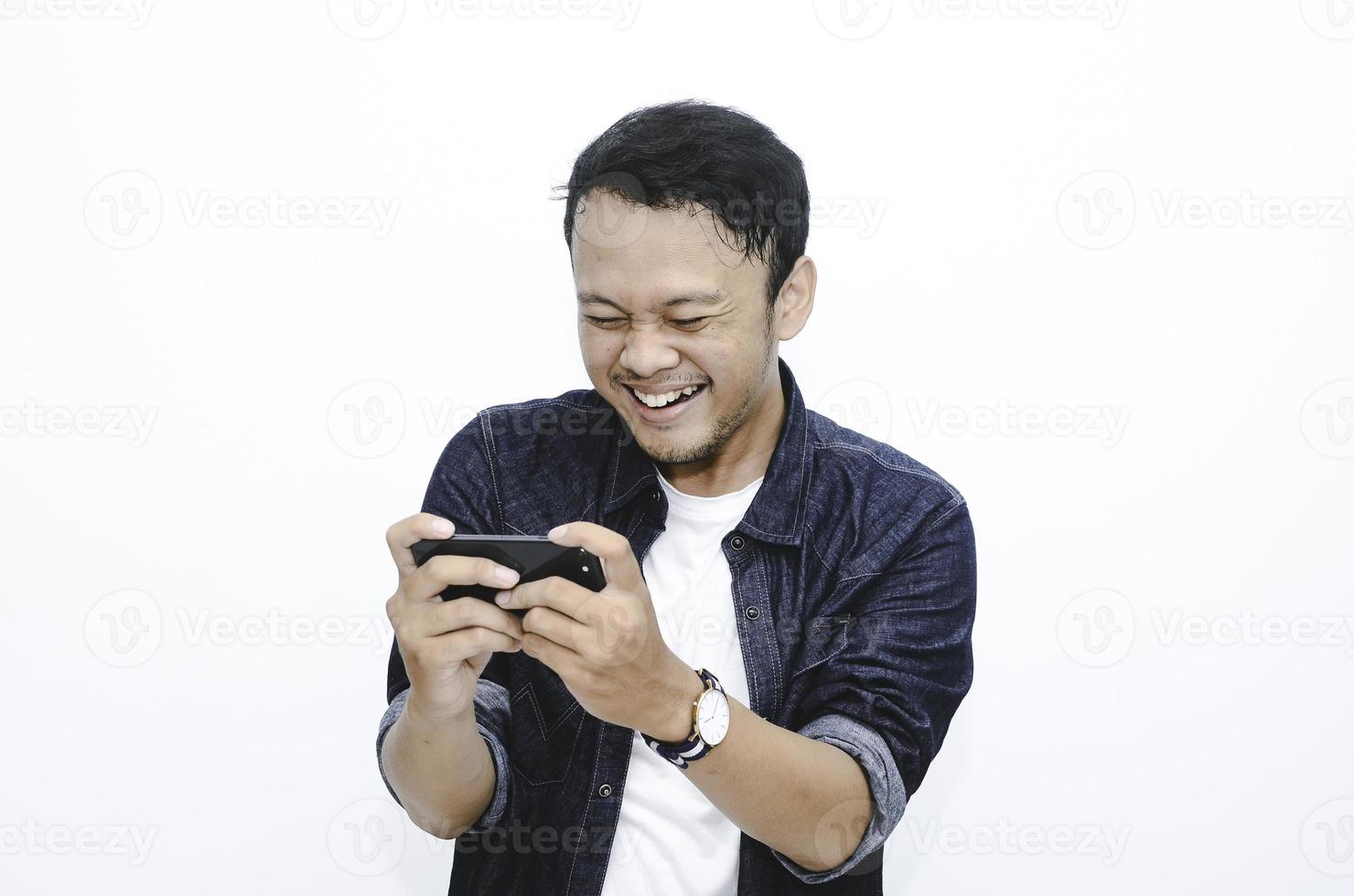 Smile and happy face of Young Asian man when playing game at phone in hand. photo