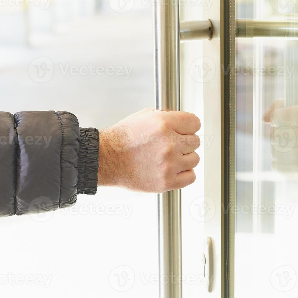 Man takes door handle with his hand and opens door. Place of accumulation of coronavirus, COVID-19 photo