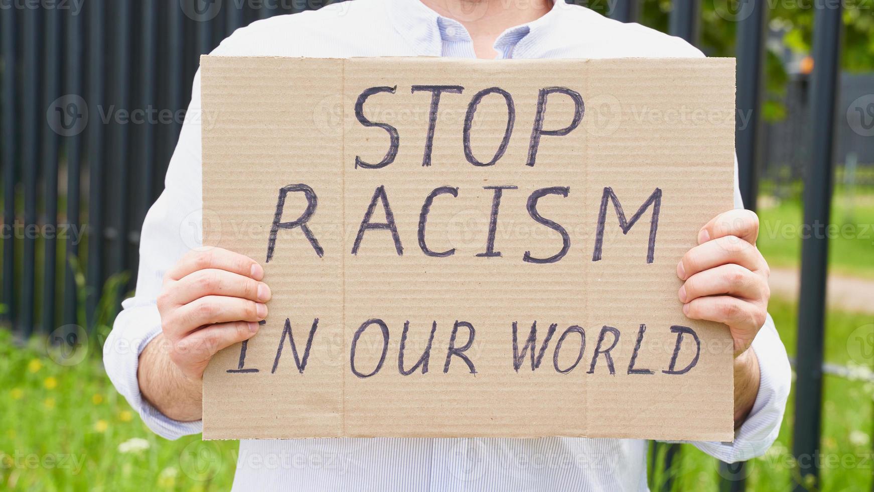 Stop racism concept. Unrecognizable white person holds sign with text against racist. photo