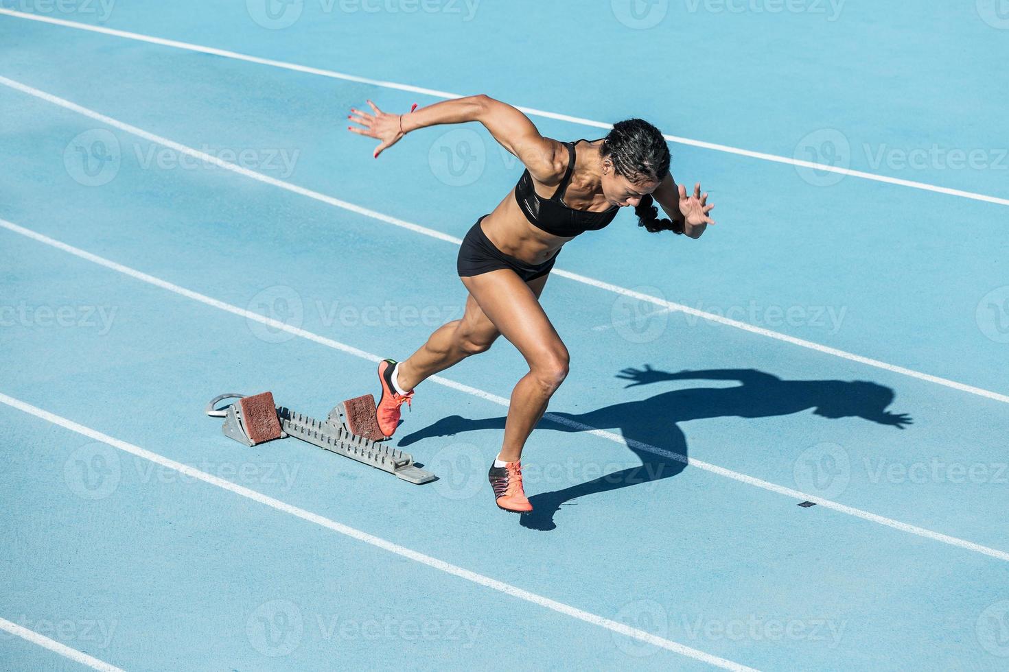 mujer joven entrenando en pista de atletismo foto