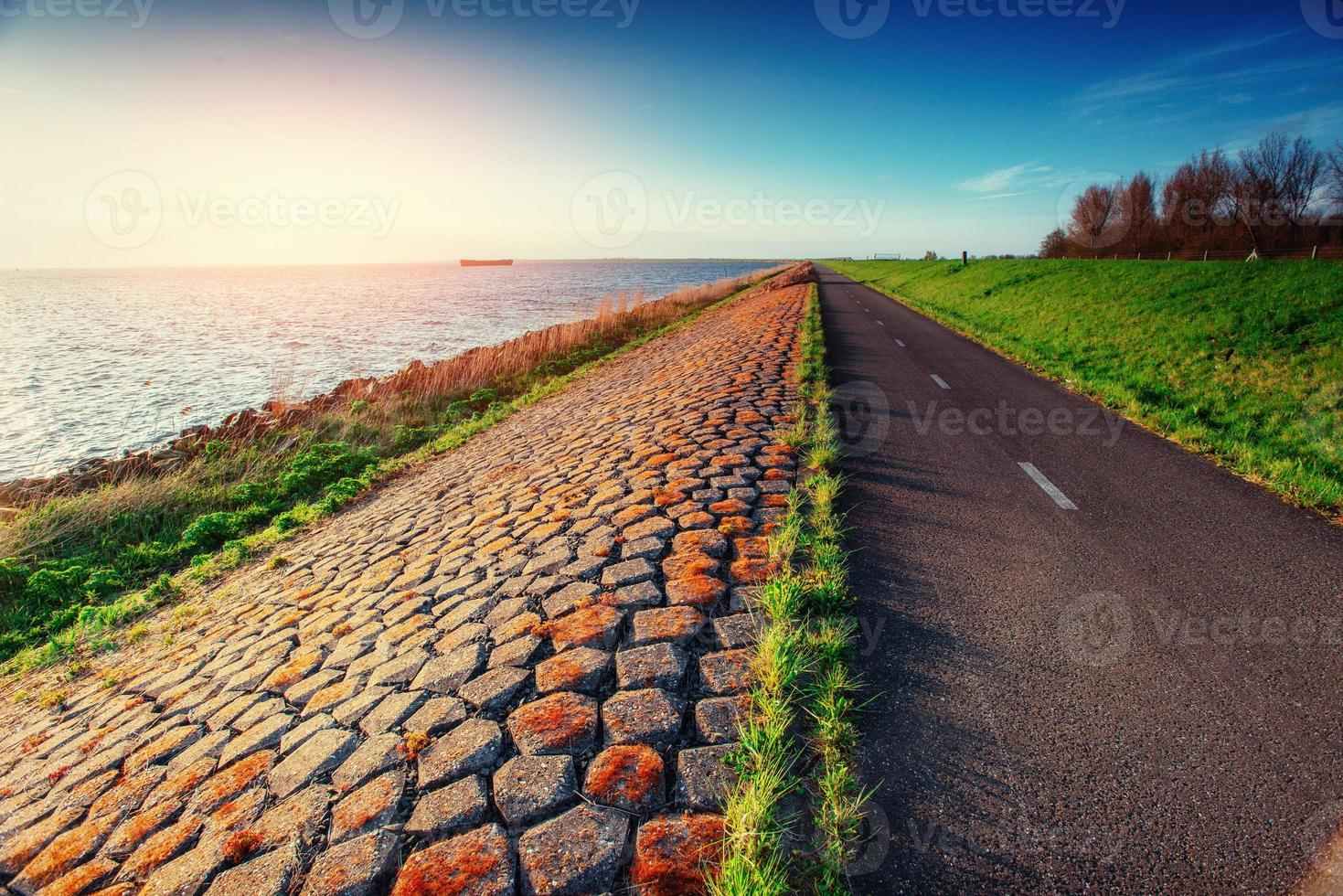 Asphalt road along the sea at sunset photo